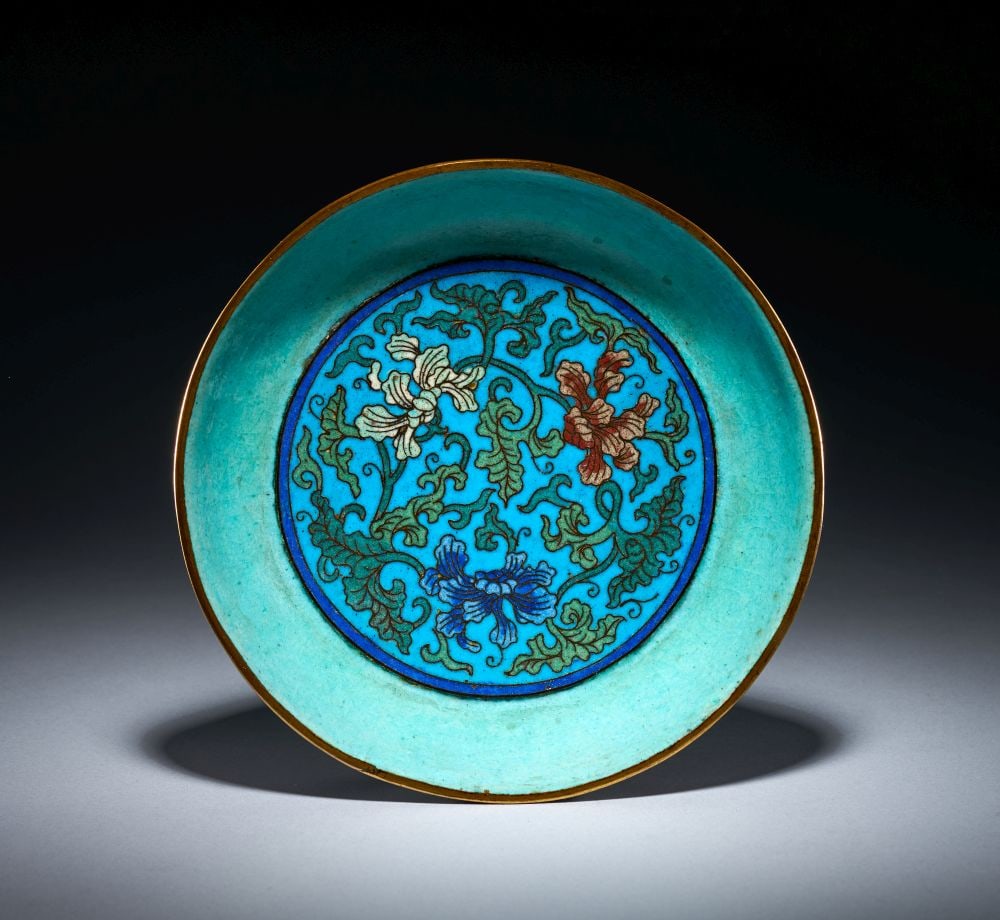 AN UNUSUAL SMALL CLOISONNÉ ENAMEL DISH, MING DYNASTY (1368-1644): AN UNUSUAL SMALL CLOISONNÉ ENAMEL DISH, MING DYNASTY (1368-1644) The small dish is worked in cloisonné enamel, of shallow circular form with a broad, gently sloping well and gilt-metal r