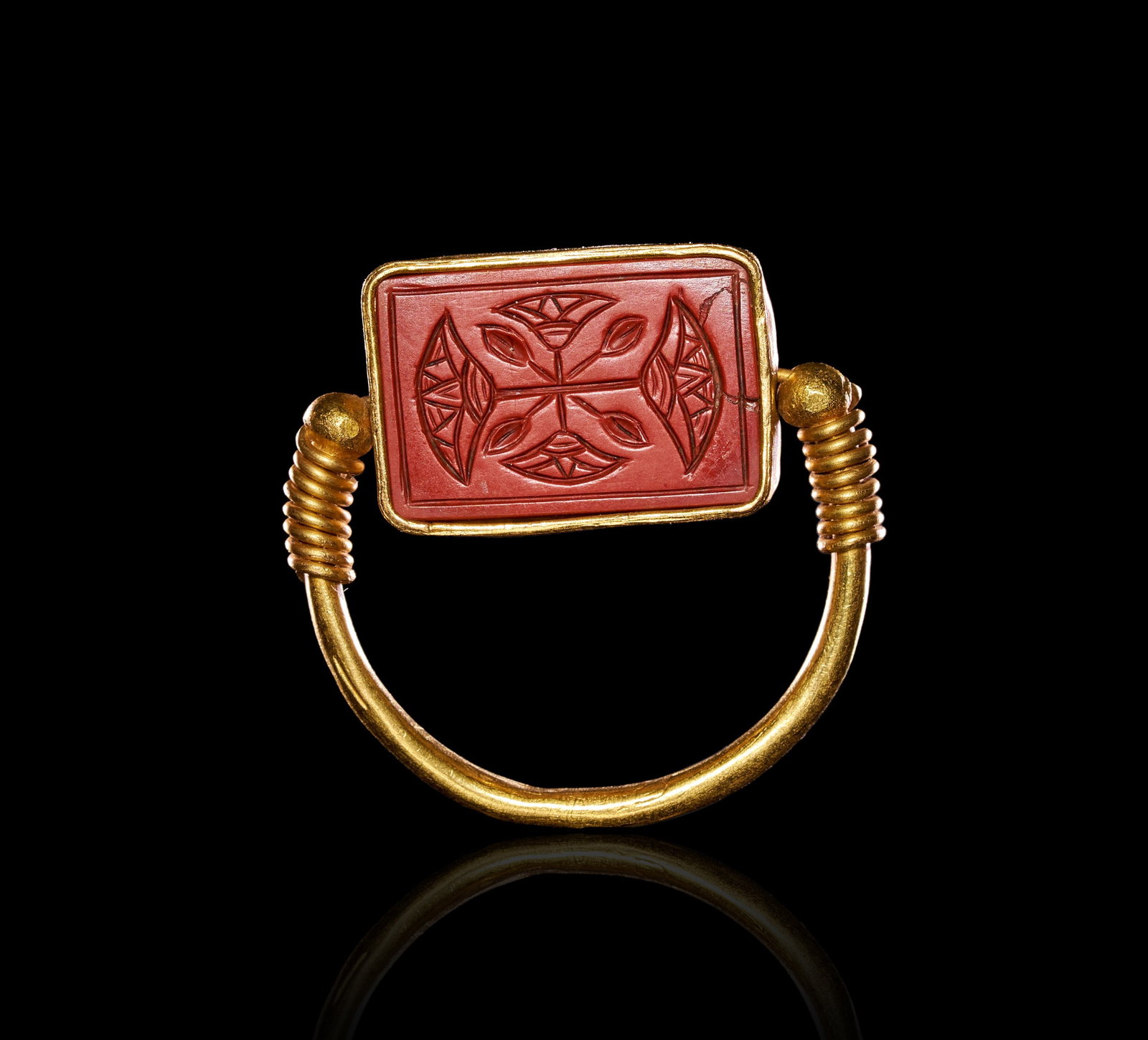 AN EGYPTIAN GOLD AND CARNELIAN SCARAB SWIVEL RING NEW KINGDOM, 19TH-20TH DYNASTY, CIRCA 1279: AN EGYPTIAN GOLD AND CARNELIAN SCARAB SWIVEL RING, NEW KINGDOM, 19TH-20TH DYNASTY, CIRCA 1279 B.C.Of swivel type, the plain gold hoop tapering to slender terminals that pass through the long axis of a