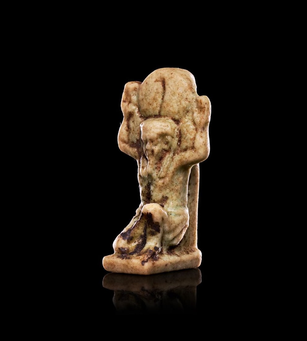 AN EGYPTIAN FAIENCE AMULET OF SHU, NEW KINGDOM, DYNASTY XVIII, CIRCA 1353-1336 B.C.: AN EGYPTIAN FAIENCE AMULET OF SHU, NEW KINGDOM, DYNASTY XVIII, CIRCA 1353-1336 B.C. Modelled in the round against a flat back plate, the small amulet depicts the god Shu kneeling on one knee, his arms