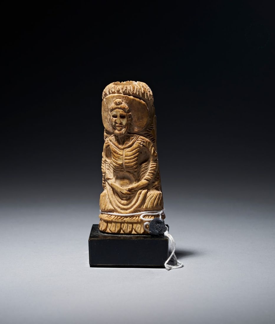 A FINE CARVED BONE FIGURINE OF A FASTING BUDDHA, GANDHARA, 2ND/3RD CENTURY: A GANDHARAN CARVED BONE FIGURE OF THE FASTING BUDDHA, ANCIENT REGION OF GANDHARA, 2ND/3RD CENTURY A.D. Carved from a section of bone retaining the natural curvature of the shaft, the figure is shown s