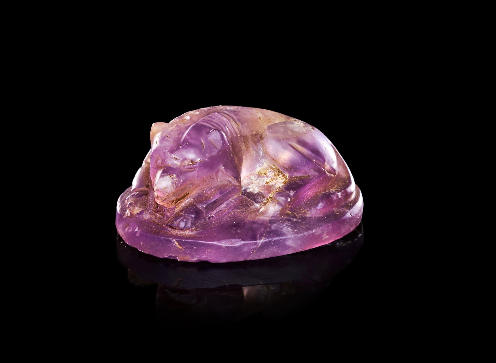 A ROMAN, AMETHYST SEAL DEPICTING A RECUMBENT HOUND, CIRCA 2ND-3RD CENTURY A.D.: A ROMAN AMETHYST SEAL DEPICTING A RECUMBENT HOUND, CIRCA 2ND-3RD CENTURY A.D. Of domed oval form, carved in the round from a translucent stone of pale violet tone, the upper surface worked into the fi