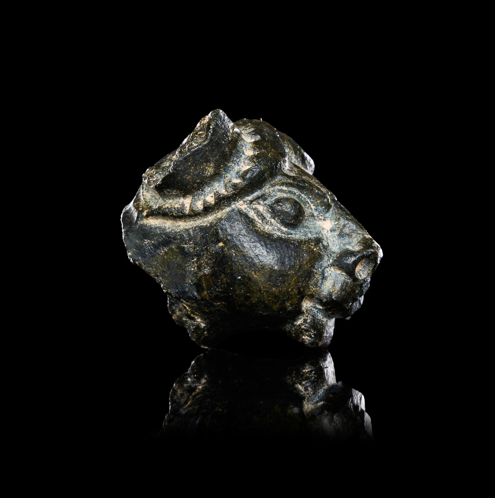A MESOPOTAMIAN SERPENTINE BULL HEAD: A MESOPOTAMIAN SERPENTINE BULL HEAD, MESOPOTAMIA, DATE TO BE CONFIRMEDCarved from a dark green serpentine of mottled surface, the head frontal and symmetrical, the muzzle short and blunt with softly m