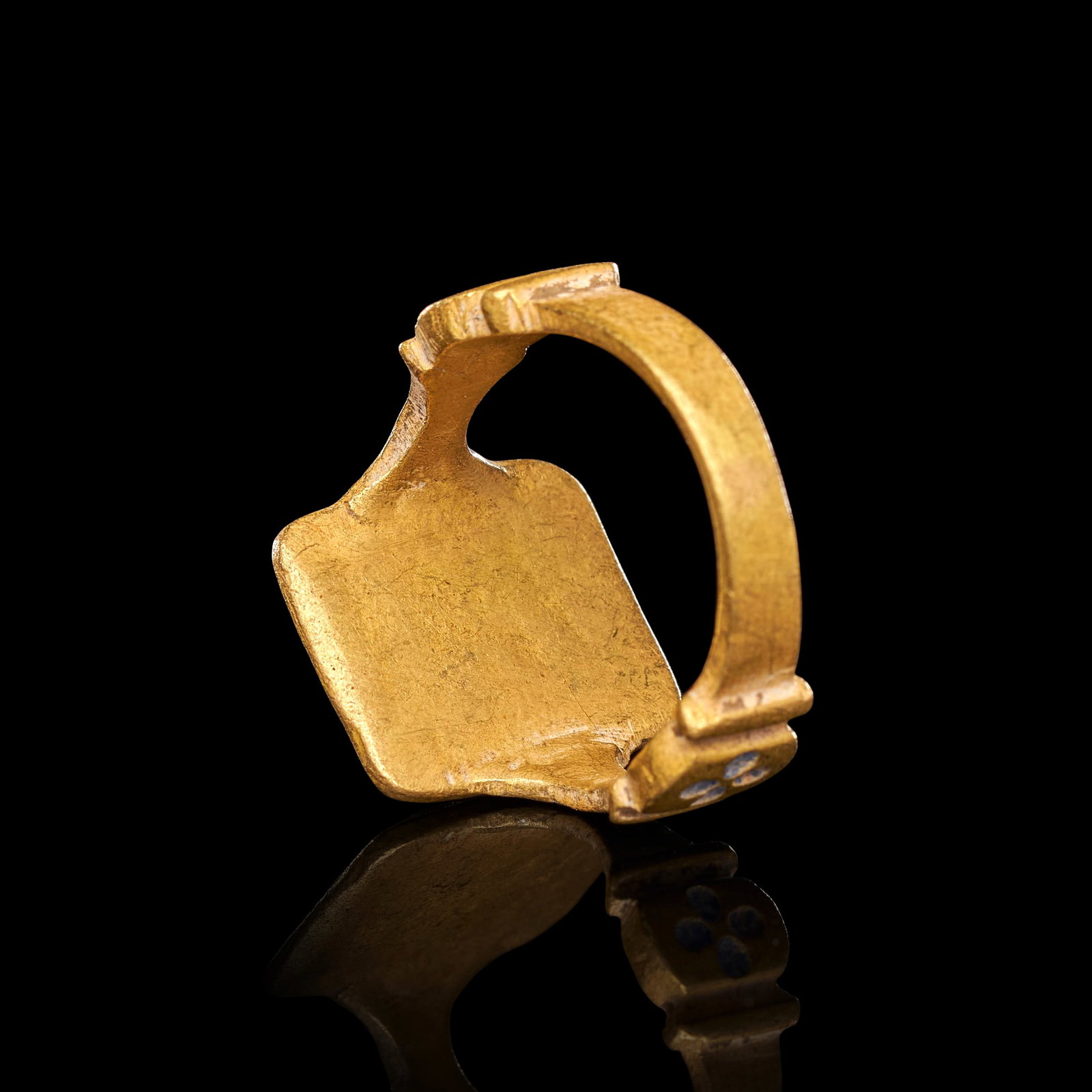 A MEDIEVAL GOLD & ENAMEL DECORATED RING, CIRCA 12TH-13TH CENTURY: A MEDIEVAL GOLD AND ENAMEL DECORATED RING, CIRCA 12TH-13TH CENTURYOf substantial construction, the ring formed with a broad rectangular bezel raised on shouldered supports above a plain hoop. The beze
