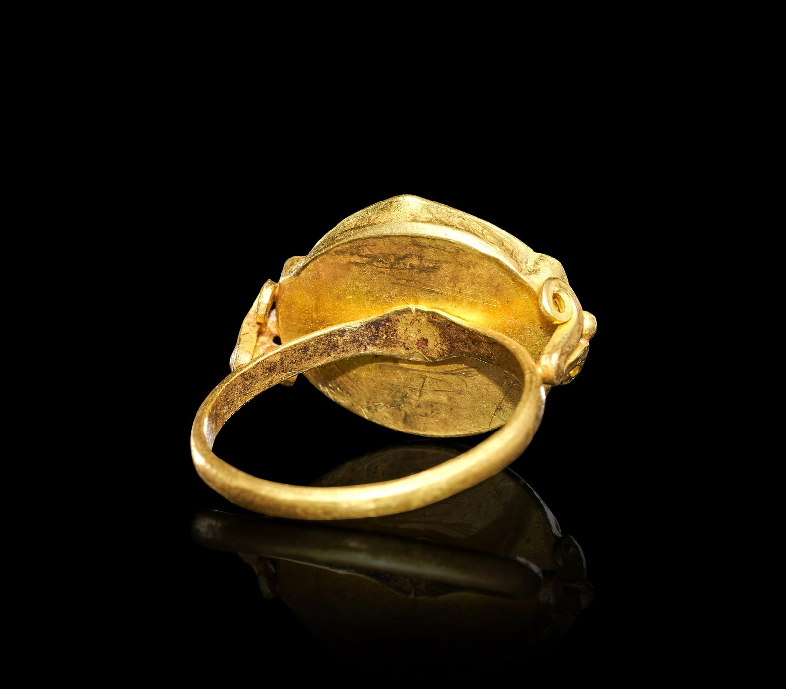 A BYZANTINE GOLD & ENAMEL "FISH" RING, CIRCA 7TH-9TH CENTURY A.D.: A BYZANTINE GOLD AND ENAMEL "FISH" RING, CIRCA 7TH-9TH CENTURY A.D.The plain hoop of circular section expands at the shoulders into scrolled volutes, each terminating in a small applied bead, and rise