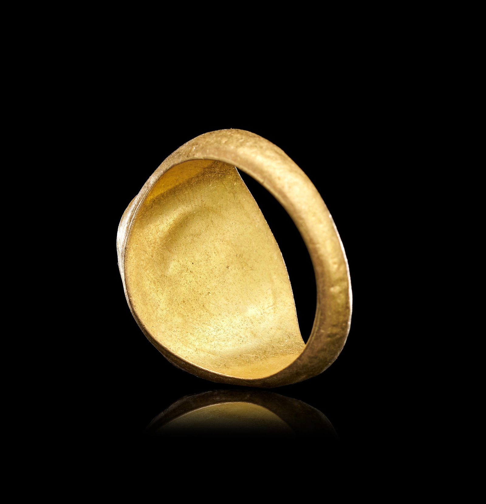 A ROMAN GOLD & CARNELIAN INTAGLIO RING: A ROMAN GOLD AND CARNELIAN INTAGLIO RING, CIRCA 1ST-2ND CENTURY A.D.The ring of solid gold construction, the plain hoop of D-section rising from a narrow band at the base to broad, sloping shoulders t