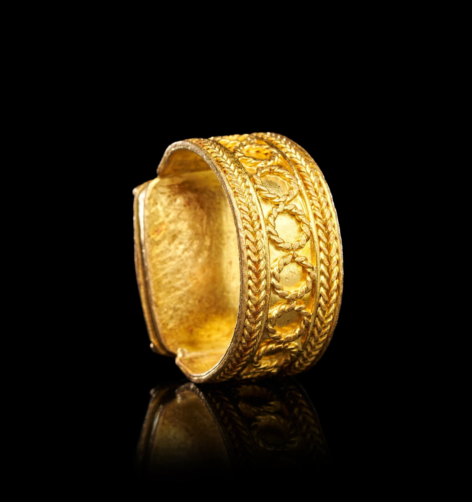 A ROMAN GOLD & CARNELIAN INTAGLIO RING DEPICTING ATHENA: A ROMAN GOLD AND CARNELIAN INTAGLIO RING DEPICTING ATHENA, CIRCA 2ND-3RD CENTURY A.D.The ring of substantial form, the broad hoop of sheet gold expanding at the shoulders to support a raised oval beze