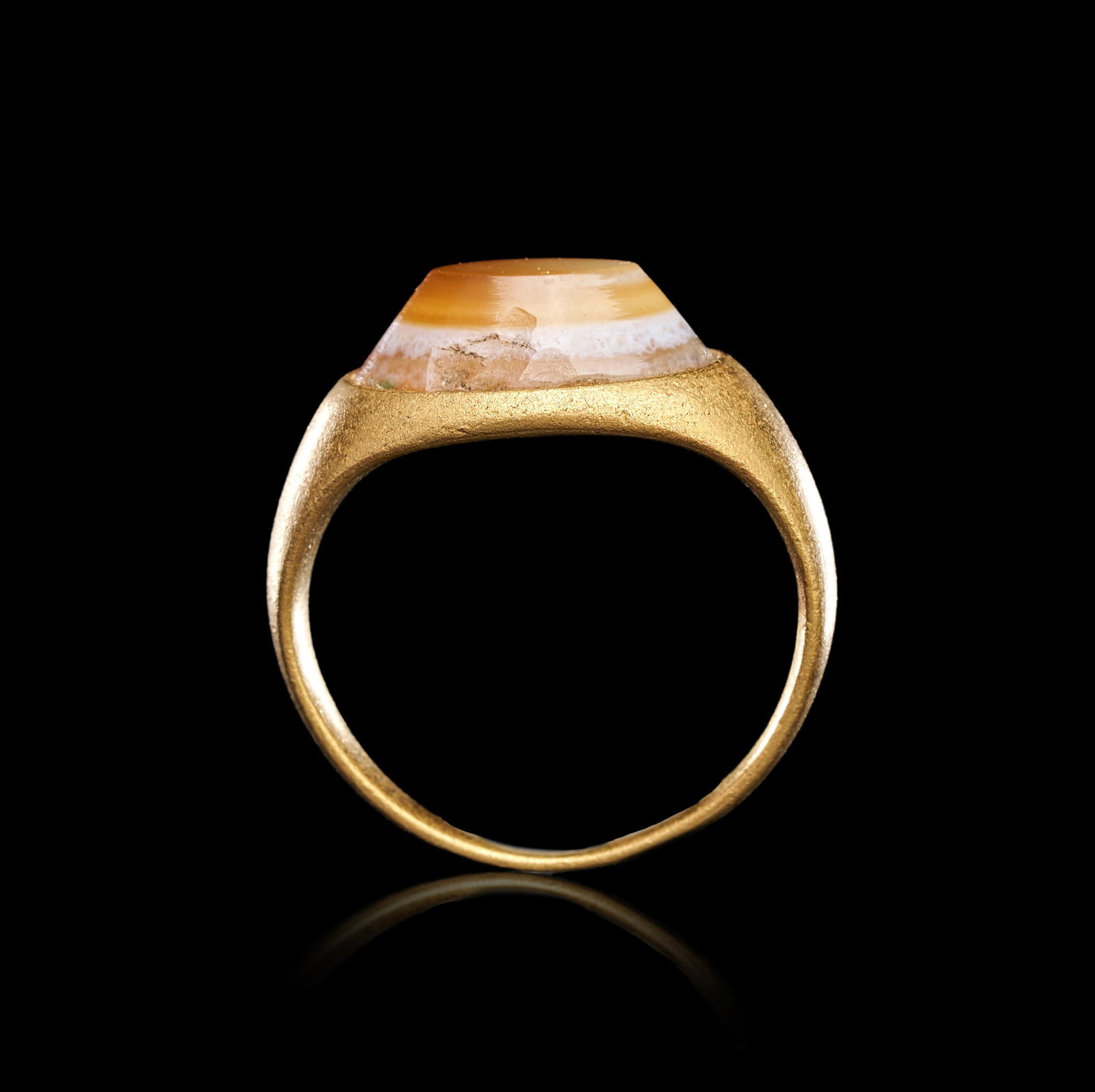 A ROMAN GOLD AGATE "DZI" BEAD RING, CIRCA 1ST CENTURY A.D.: A ROMAN GOLD AGATE "DZI" BEAD RING, CIRCA 1ST CENTURY A.D.A substantial Roman ring featuring a pierced agate "Dzi" bead, set horizontally within a high-karat gold frame. The bead is banded with natura
