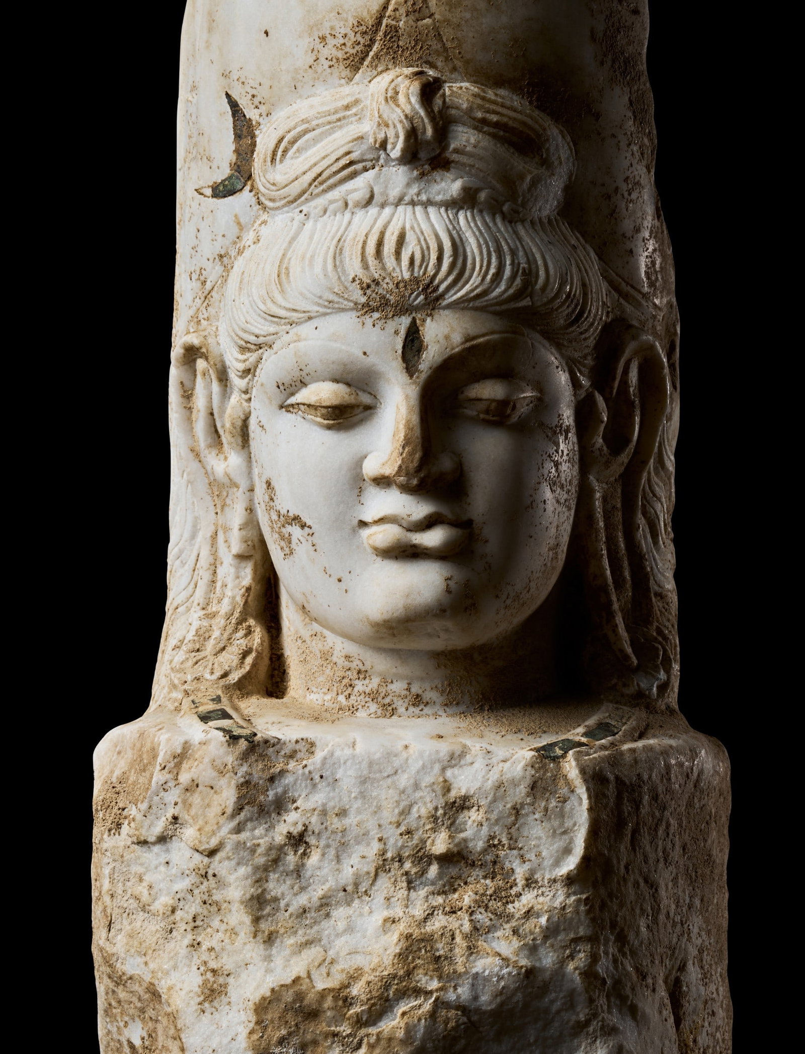 A MARBLE HEAD OF SHIVA, HINDU SHAHI, NORTHWEST INDIA OR GANDHARA AFGHANISTAN, CIRCA 7TH–9TH: A MARBLE HEAD OF SHIVA, HINDU SHAHI, NORTHWEST INDIA OR GANDHARA AFGHANISTAN, CIRCA 7TH-9TH CENTURYCarved from a single block of white marble, the head rises from an unworked rectangular stump that wo