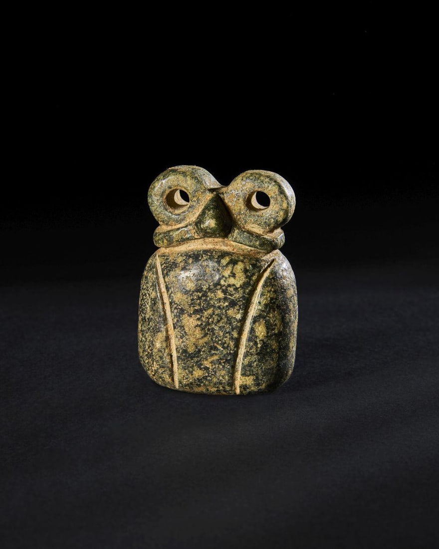 A MARBLE DOUBLE “EYE?? IDOL Tell Brak Region, Circa 3500–3300 B.C.: A MARBLE DOUBLE “EYE” IDOLTell Brak Region, Circa 3500–3300 B.C.Carved from creamy-grey marble with darker mottling, this compact figure displays the characteristic form of the Tell Brak “