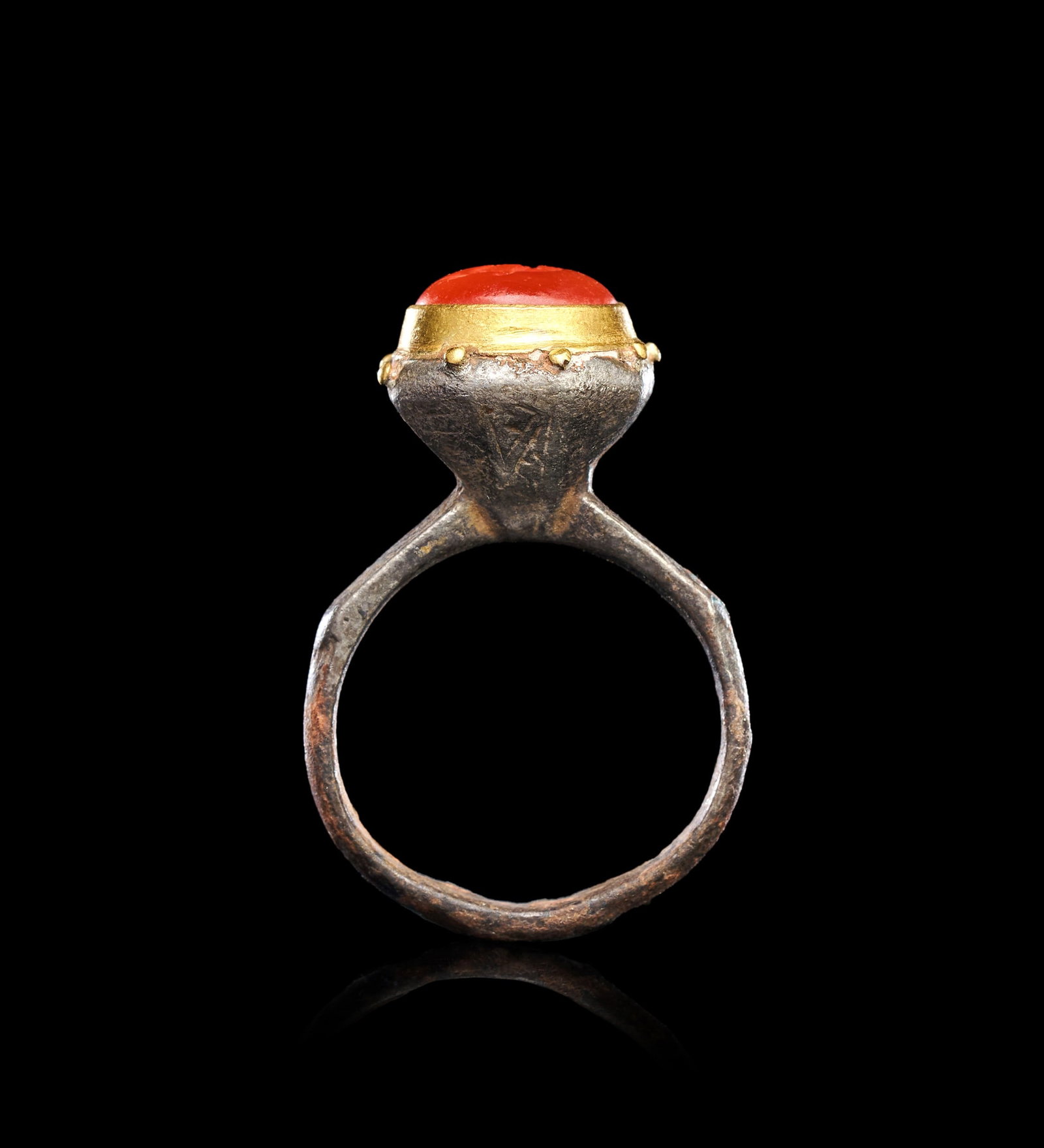 A GREEK SILVER & NIELLO INTAGLIO RING DEPICTING A CUPID: A GREEK SILVER AND GOLD RING WITH CARNELIAN INTAGLIO OF CUPID RIDING A DOLPHIN, HELLENISTIC WORLD, CIRCA 3RD-1ST CENTURY B.C.Of substantial form, the silver hoop rising from a plain shank incised on t
