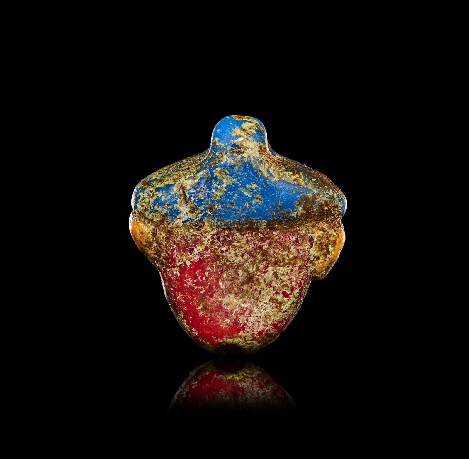 A PHOENICIAN GLASS HEAD PENDANT CIRCA 6TH-3RD CENTURY B.C.: A PHOENICIAN POLYCHROME GLASS HEAD PENDANT, EASTERN MEDITERRANEAN, CIRCA 6TH-3RD CENTURY B.C.Of small scale and modelled in the round, the pendant formed as a bearded or hooded human head with a broad