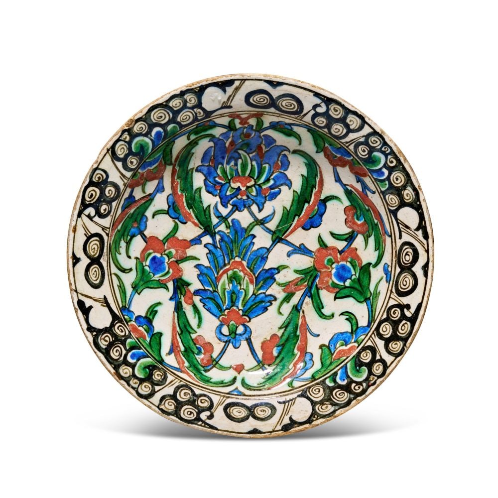 AN IZNIK POTTERY DISH, 17TH CENTURY, CIRCA 1680, TURKEY: AN IZNIK POLYCHROME POTTERY DISH, TURKEY, 17TH CENTURY, CIRCA 1680 The fritware body is painted in cobalt blue, bole red, and green, with black outlines, beneath a clear glaze. The visible decoration 