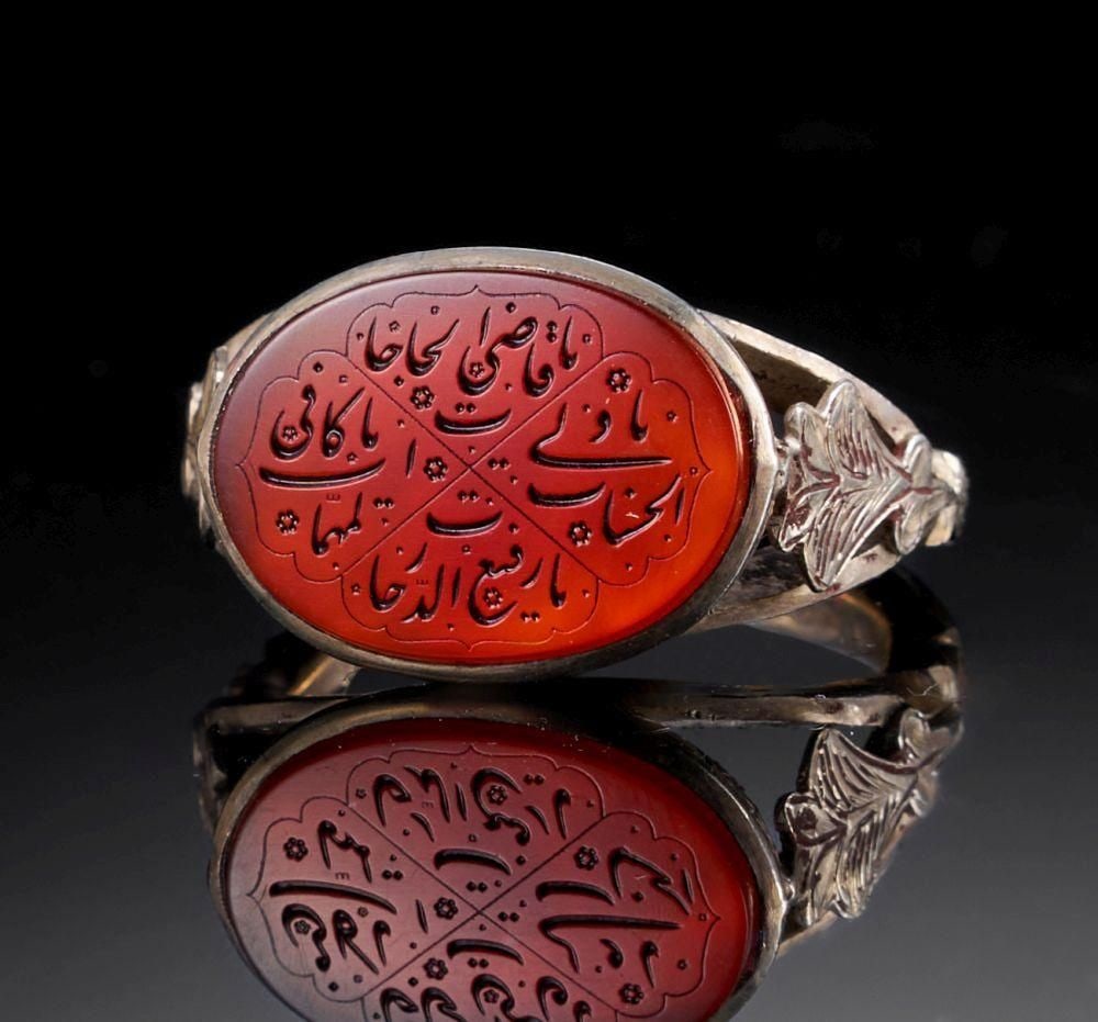 A CARNELIAN CALLIGRAPHIC INSCRIBED RING ON SILVER, 19TH CENTURY, PERSIA: A CARNELIAN CALLIGRAPHIC INSCRIBED RING ON SILVER, 19TH CENTURY, PERSIA This refined silver ring is set with an oval carnelian plaque of rich reddish-orange tone, intricately engraved with a calligrap