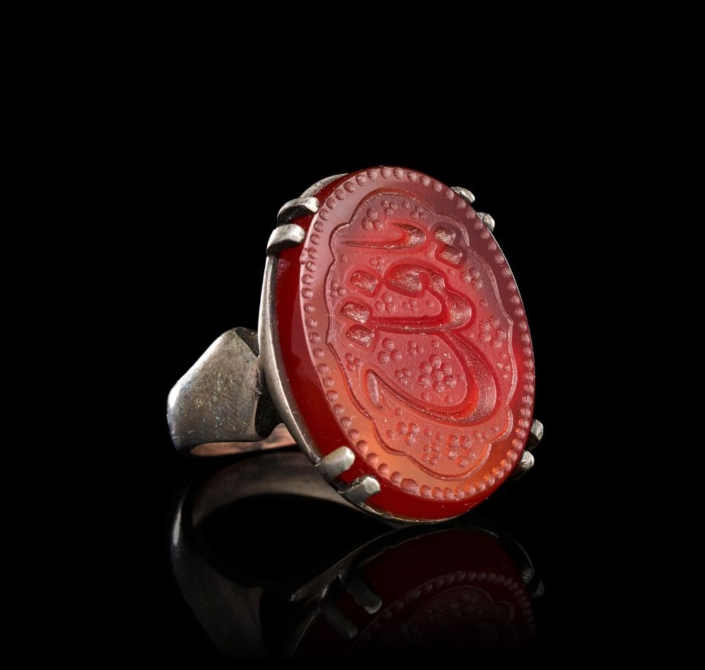 A CALLIGRAPHIC INSCRIBED AGATE RING ON SILVER, 19TH CENTURY, PERSIA: A CALLIGRAPHIC INSCRIBED AGATE RING ON SILVER, PERSIA, 19TH CENTURY The ring of substantial form, the broad hoop tapering from a flat, faceted shoulder to a narrow band, surmounted by a large oval car