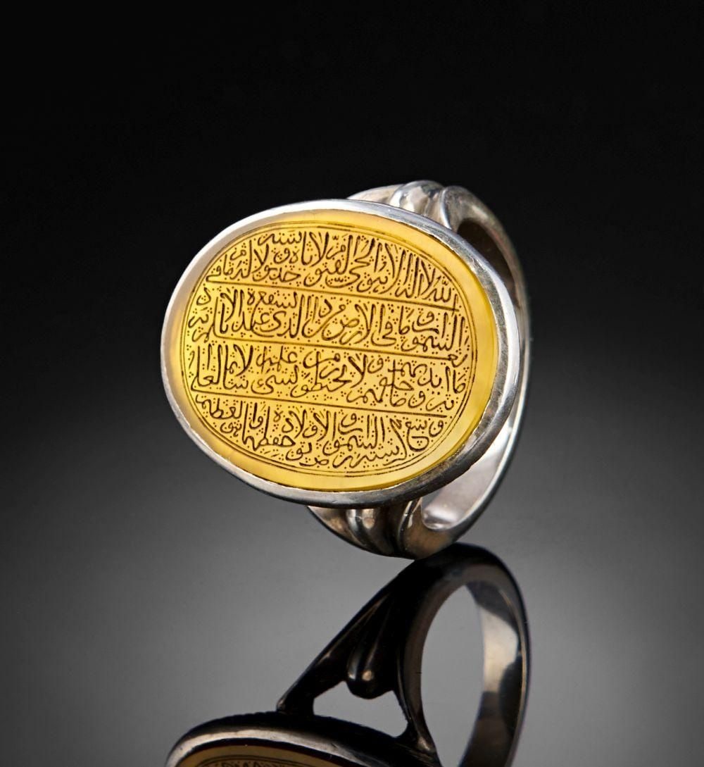 A CALLIGRAPHIC INSCRIBED AGATE RING, 19TH CENTURY, PERSIA: A CALLIGRAPHIC INSCRIBED AGATE RING, PERSIA, 19TH CENTURY Of oval bezel form, the honey-toned agate set within a plain silver collet raised on a bifurcated shank with plain shoulders. The stone is eng
