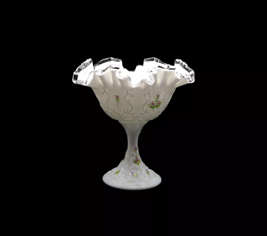 Fenton Art Glass “Violets in the Snow” Spanish Lace Round Compote: Fenton Art Glass “Violets in the Snow” Spanish Lace round compote featuring a delicate ruffled edge and hand-painted violets. Standing 6 3/4 inches tall, it showcases intricate craftsmanship a