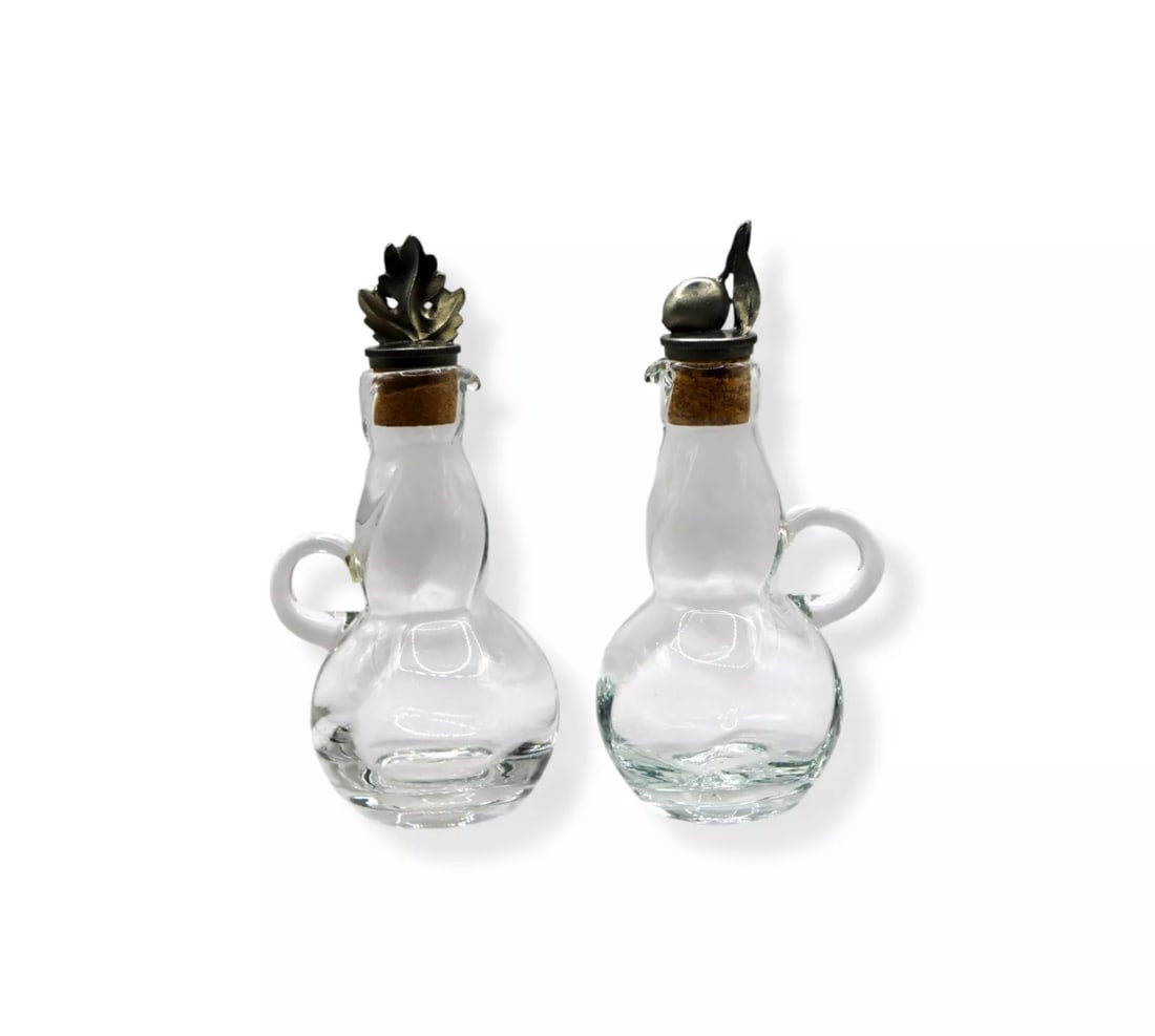 Vintage Glass Cruet Set w/ Pewter Olive & Oak Leaf Design Figural Stoppers: Vintage Glass Cruet Set with Pewter Olive & Oak Leaf Design Figural Stoppers, each measuring 6 1/4 inches tall. These elegant glass cruets feature a gracefully curved body with a sturdy handle, topped