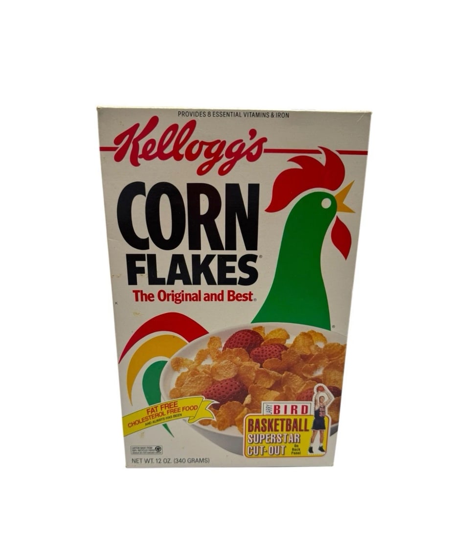 Vintage 1993 Kellogg’s Corn Flakes Empty Cereal Box Ft. Larry Bird Cutout: The product is a vintage 1993 Kellogg's Corn Flakes empty cereal box featuring a Larry Bird cutout. This collectible advertising item is original and showcases the multi-color design typical of cereal