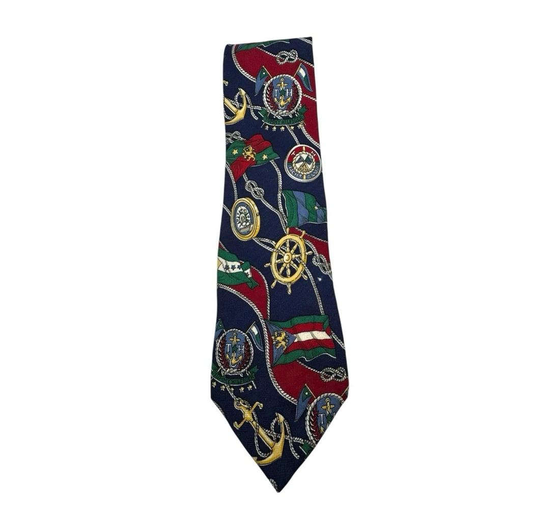 Vintage Tommy Hilfiger 100% Italian Silk Blue Nautical Flags Tie: The Vintage Tommy Hilfiger 100% Italian Silk Blue Nautical Flags Tie is a classic and stylish accessory for men. Made from luxurious silk with a nautical theme, this tie features blue flags with the i