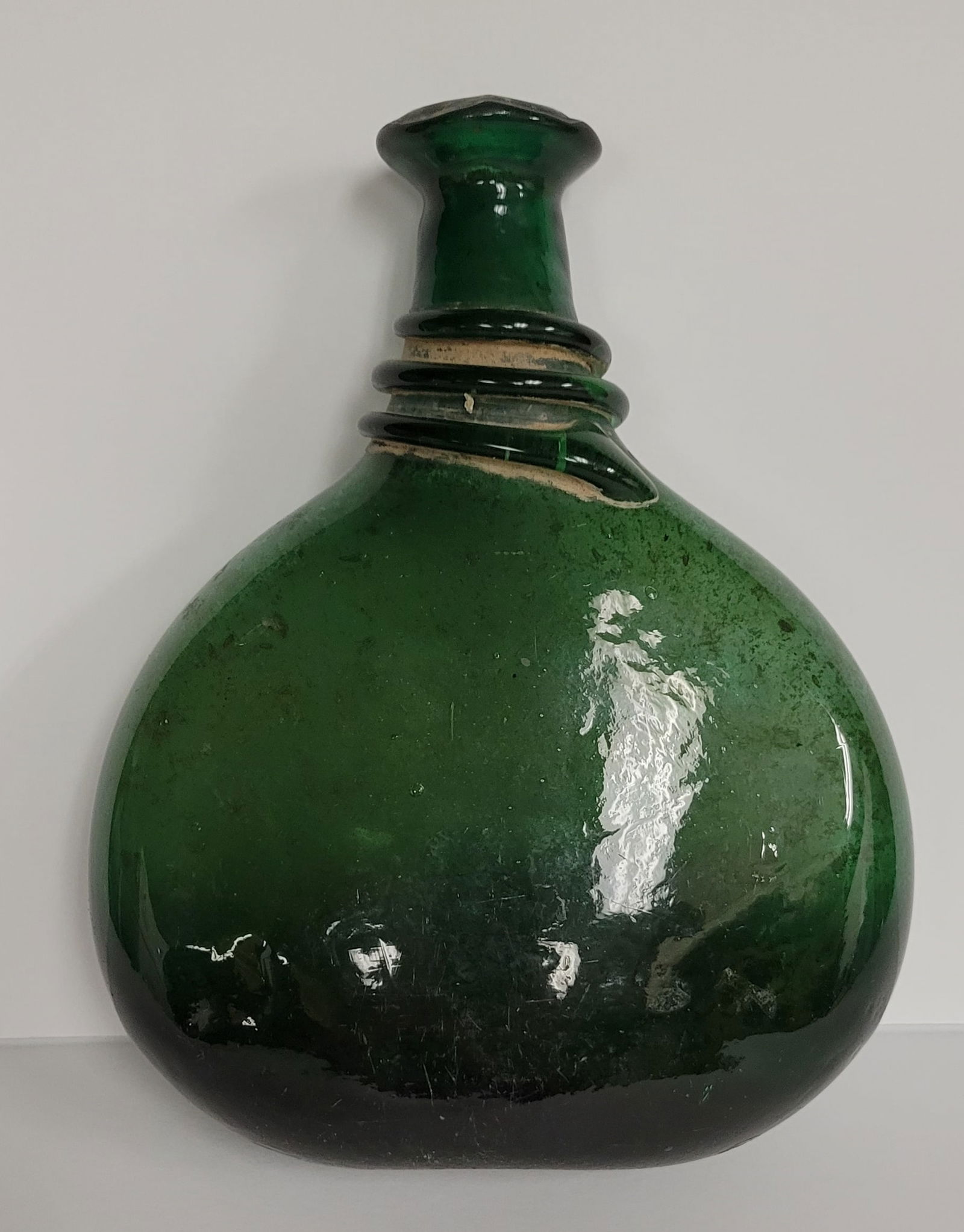 Rare 17th c. Saddle Flask/Bottle in a deep green: Rare 17th c. Saddle Flask/Bottle in a deep green with spiral glass string neck. 8 3/4 tall x 7" wide x 3" deep