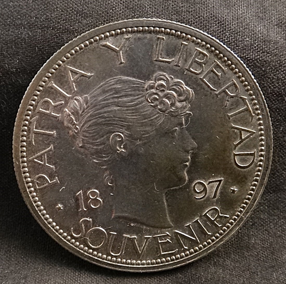 1897 Cuban 900 Fine Silver Souvenir Peso – UNC: Scarce 1897 Cuban 900 Fine Silver Souvenir Peso in Uncirculated Condition (toning with age). Only 4286 Minted. Rare in MS. 36Mm Type II.