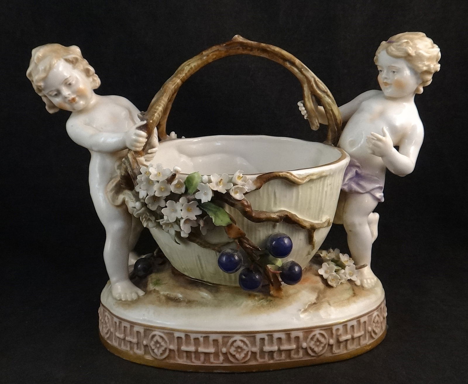 Antique German Von Schierholz HP Porcelain Basket w/2 Putti: Antique German Von Schierholz Hand Painted Porcelain Basket, 2 Putti with Branch & Handle Flowers & Fruit Basket. Impressed & Blue Von Schierholz marks on the bottom. 23k gold trim. 9 ¾”