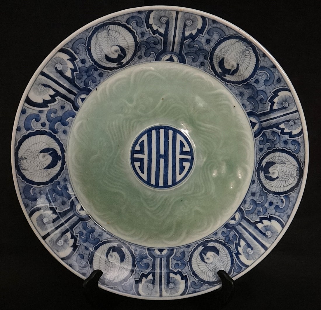 Large Antique Japanese Imari HP Porcelain Charger – Happiness Symbol: Large Antique Japanese Imari Hand Painted Porcelain Charger with a design of cranes amid floral designs with a happiness symbol in the center, Surrounded by a celadon glaze. Meiji period (1868-1912).