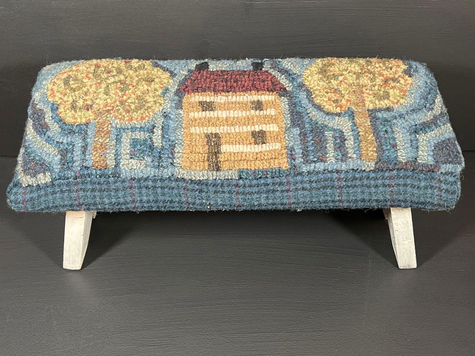 Signed Footstool & Hooked Wool Cover: White painted footstool 17” long x 7” wide x 7.5” high signed with a letter stamp John I. Madies plus a hooked wool cushioned top with house and tree design signed by Janice Sonnen 2