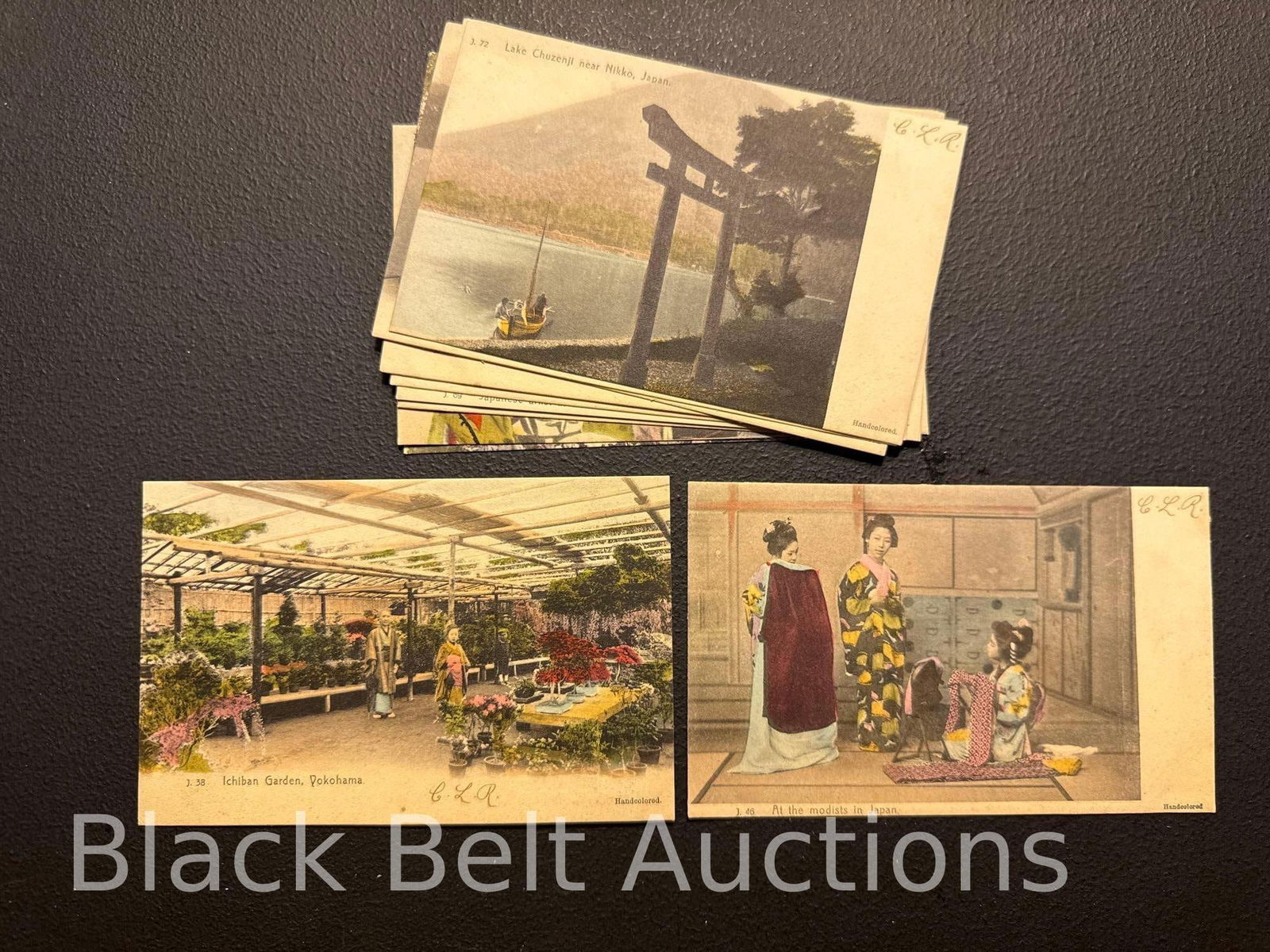 Twelve Vintage Hand Colored Japan Post Cards: Twelve vintage hand colored post cards of Japan and its people. These were produced around 1910 and have never been used. All, however, have three inked initials on the fronts of the cards.
