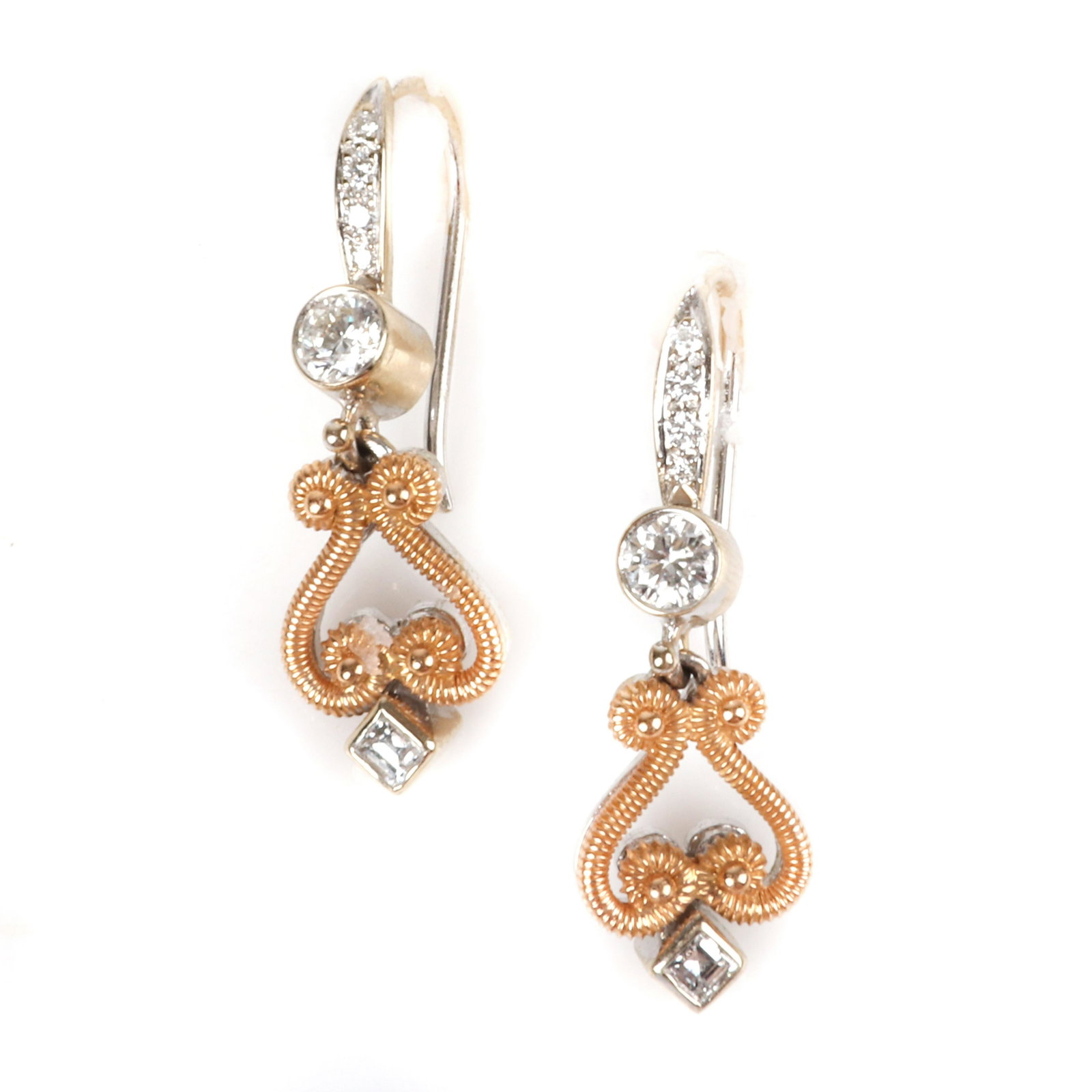 Designer 18K yellow and white gold diamond drop: Designer 18K yellow and white gold diamond drop earrings with Victorian / Edwardian Revival scroll motif, 4.00dwt. Signed with an 'M'. Containing 2 square step cut diamonds weighing .14cttw, and 10 ro