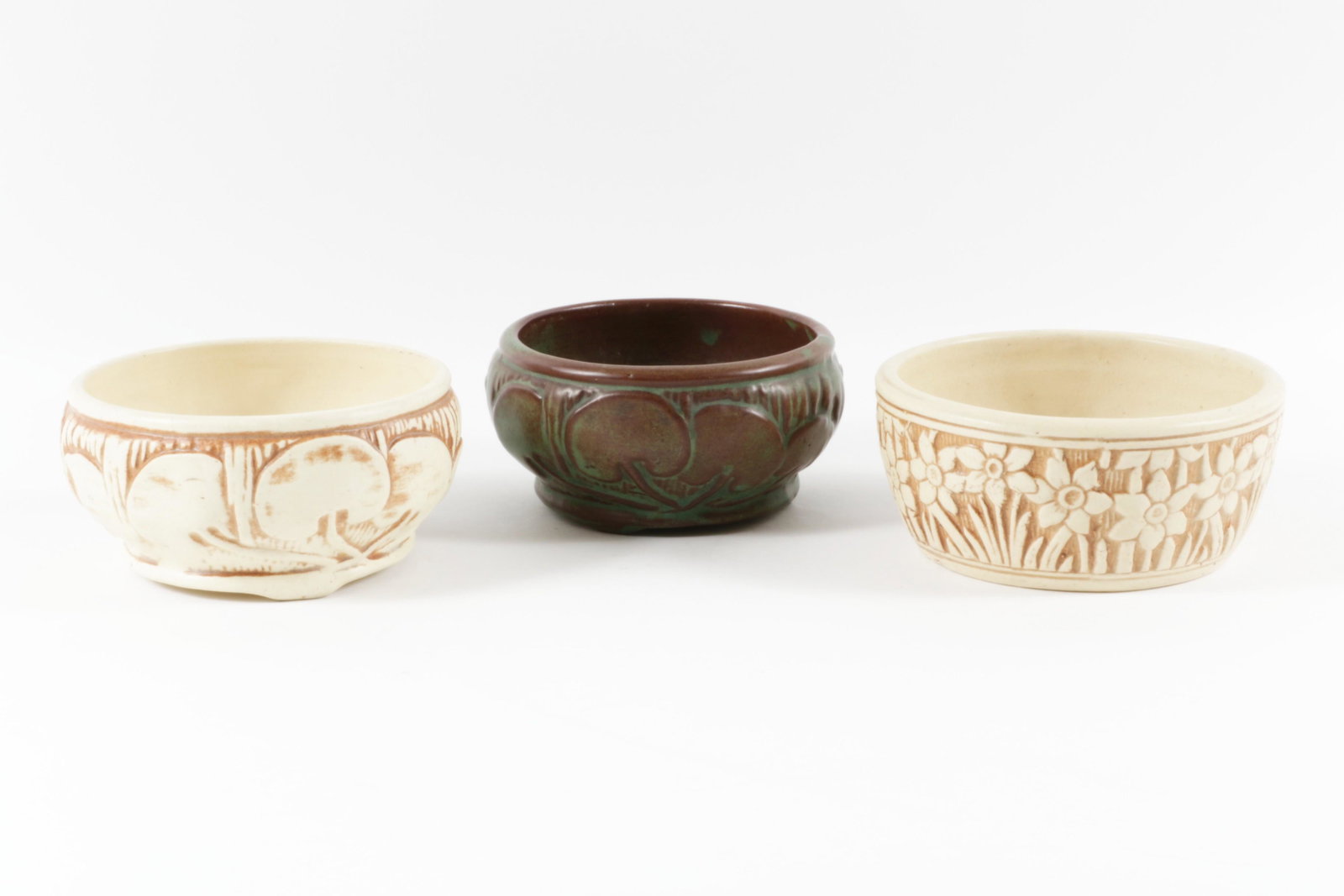 Three Weller Narcissus Bowls, Two 2 1/2â€ T x 5 1/2â€ D low bowls; ca. 1914; ivory with brown: Three Weller Narcissus Bowls Two 2 1/2” T x 5 1/2” D low bowls; ca. 1914; ivory with brown highlights glaze; lily pad and narcissus motifs; unmarked. â€œOrris” 3 footed bowl; sem