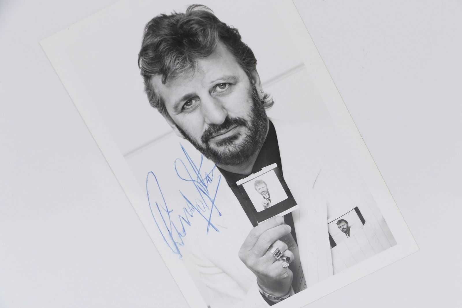 The Beatles Ringo Starr Autographed Photo: The Beatles Ringo Starr Autographed Photo The photo is a 3 1/2 by 5 1/2 photo of Ringo holding a photo of himself. Accompanied with COAs from RR Auction and Tracks.