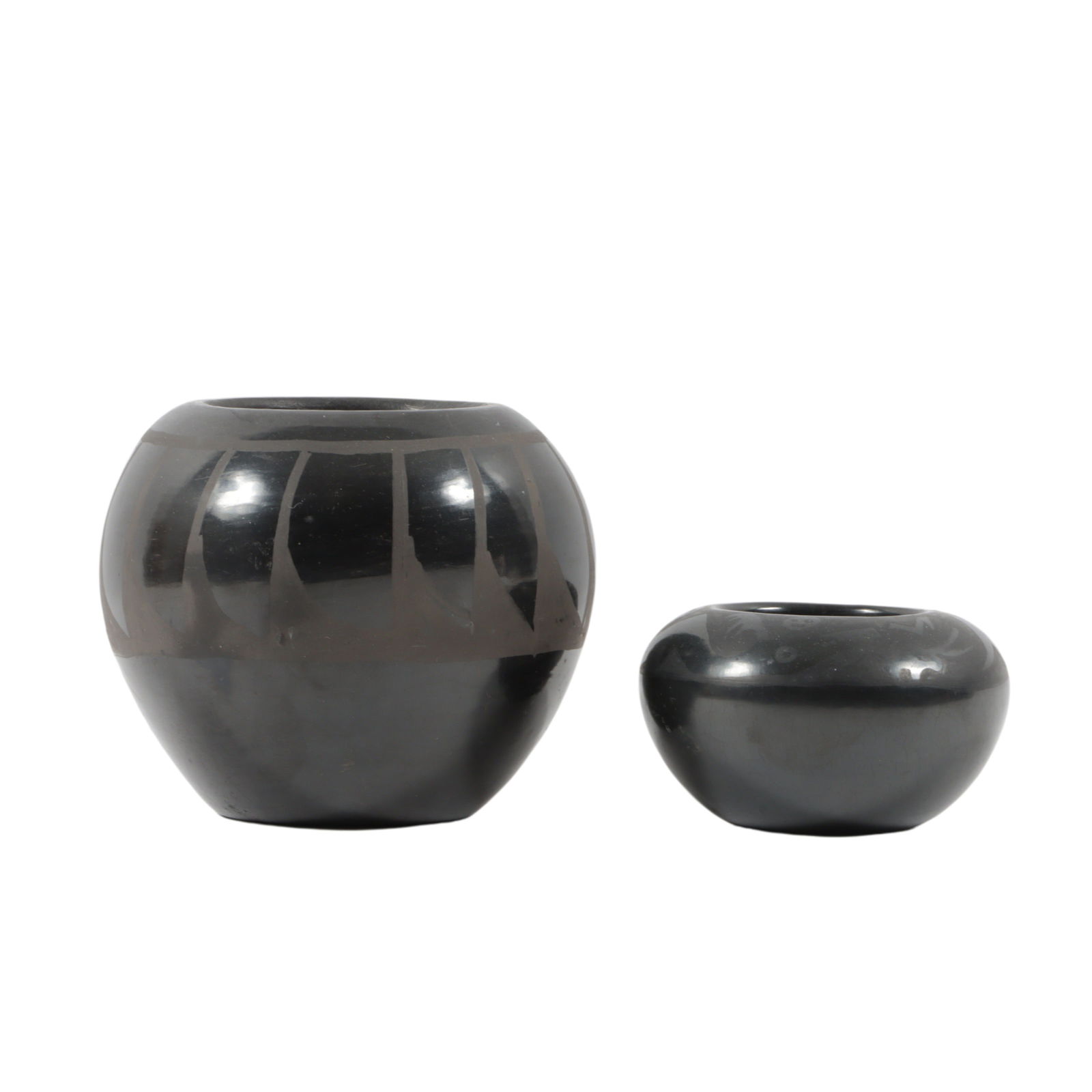 Signed San Ildefonso burnished blackware pottery 2pc group: larger jar has geometric pattern, the: Signed San Ildefonso burnished blackware pottery 2pc group: larger jar has geometric pattern, the smaller by Alfred Aguilar has design with stylized animal faces. 4"H x 4"Diam (larger)