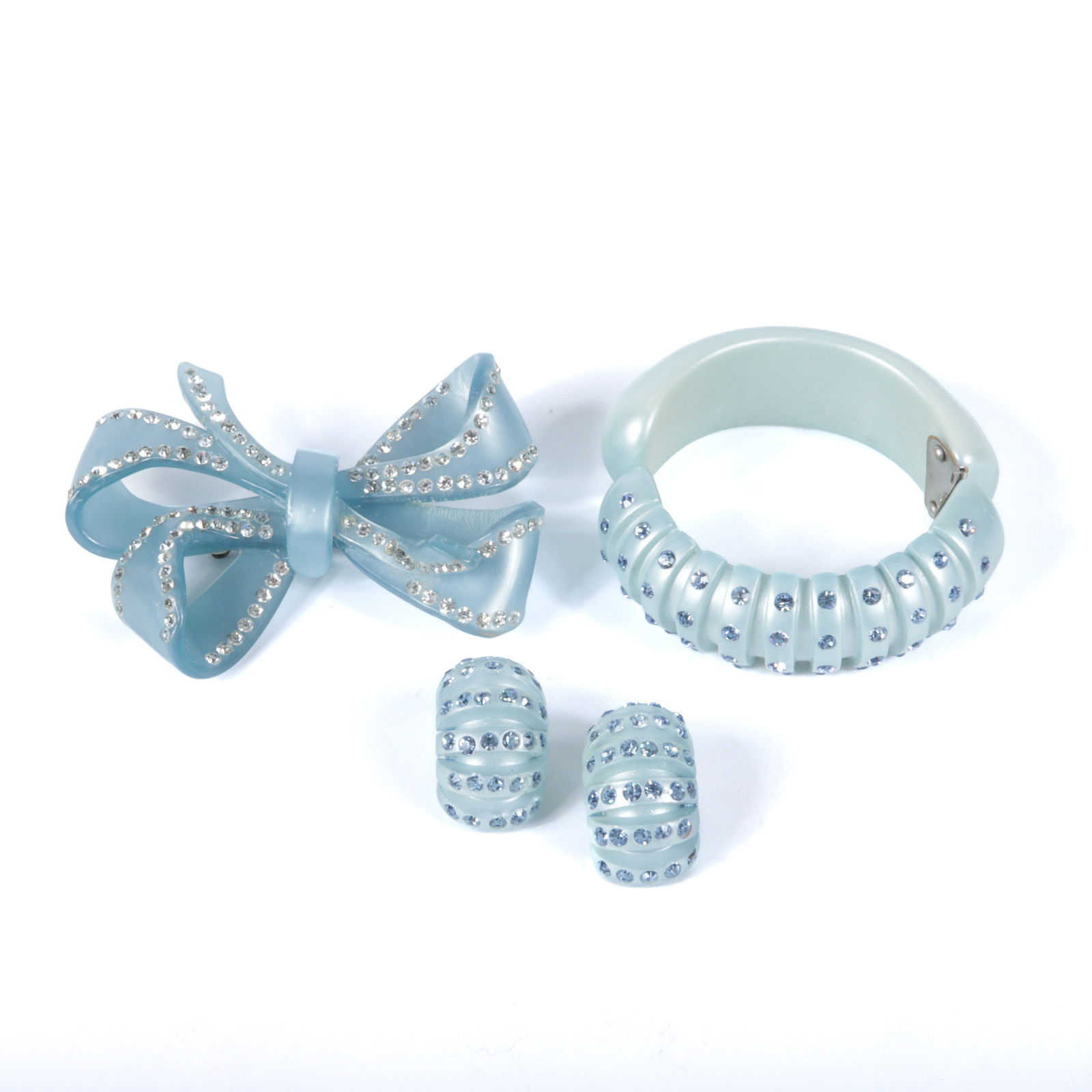 Three light blue nylon / celluloid / lucite accessories studded with rhinestones: large bow pin: Three light blue nylon / celluloid / lucite accessories studded with rhinestones: large bow pin brooch with rhinestones, and segmented pearlized blue clamper cuff bracelet and earring set with rhinest