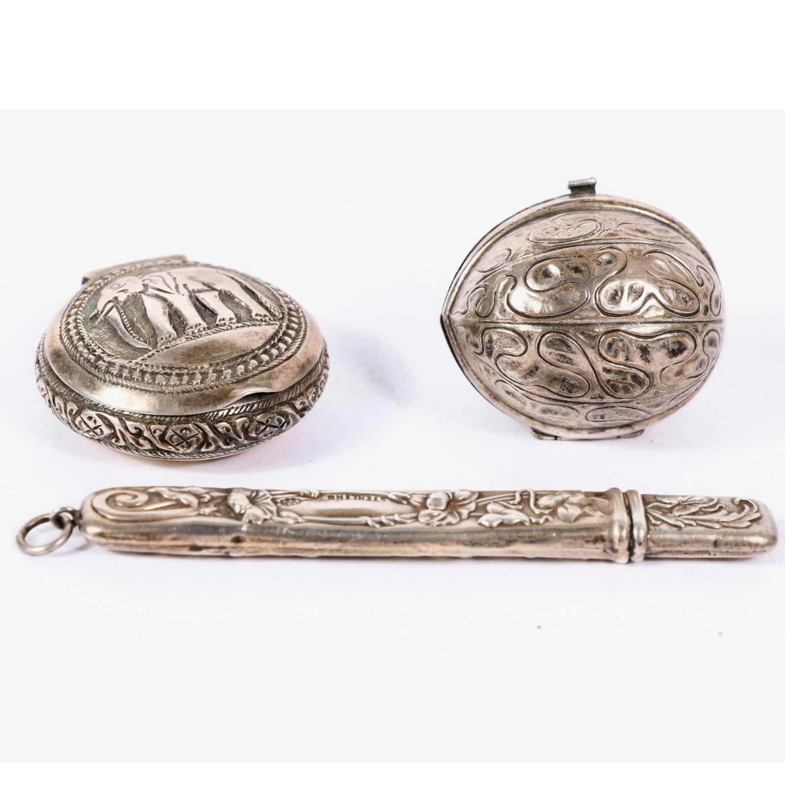 Three Victorian sterling silver vanity items: Webster chatelaine nail file with repousse case, 1"H x: Three Victorian sterling silver vanity items: Webster chatelaine nail file with repousse case, German walnut shaped trinket box / sewing accessory, snuff / pill box with repousse elephant. 1.447 Troy