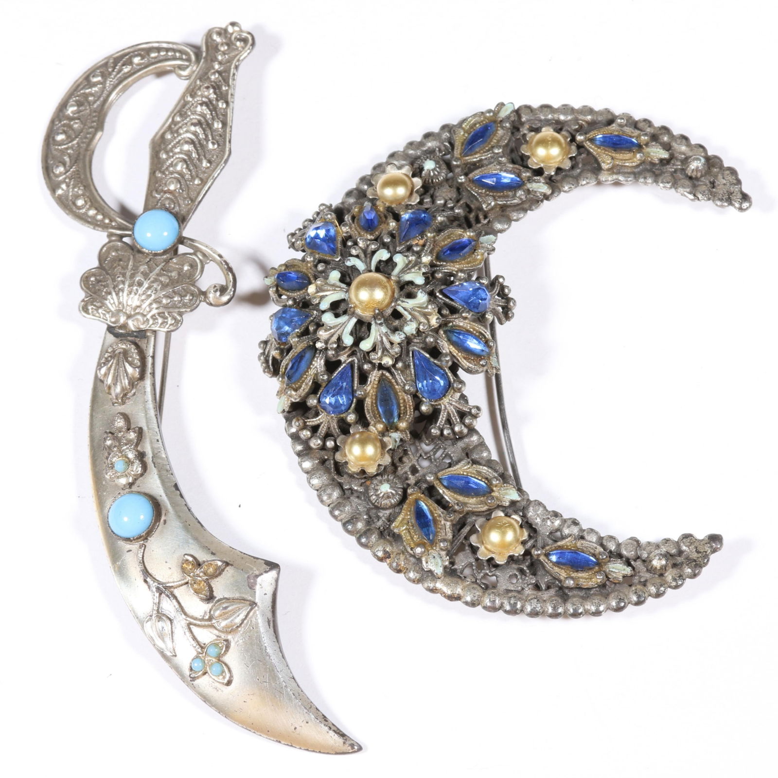 Large Korda Thief of Bagdad dimensional jeweled and enameled filigree crescent moon brooch and Coro: Large Korda Thief of Bagdad dimensional jeweled and enameled filigree crescent moon brooch and Coro scimitar brooch Some loss of enamel on scimitar flowers Provenance: From the collection of Cheryl Ki