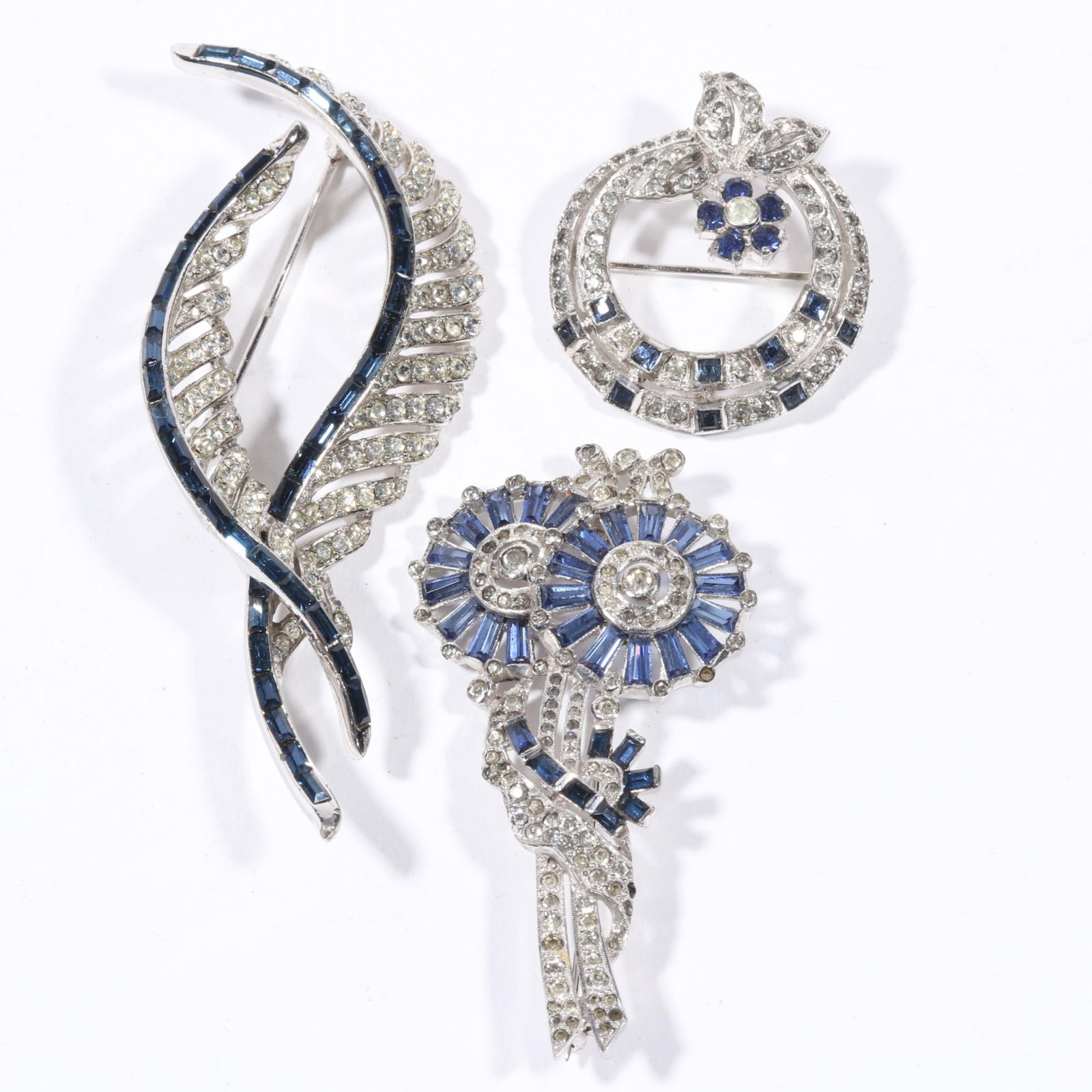 Art Deco Retro diamante jewelry group with Jomaz wreath brooch, floral brooch with blue baguette: Art Deco Retro diamante jewelry group with Jomaz wreath brooch, floral brooch with blue baguette rhinestones, and feather brooch with dark blue baguette rhinestones. Some "dead" stones. Provenance: Fr