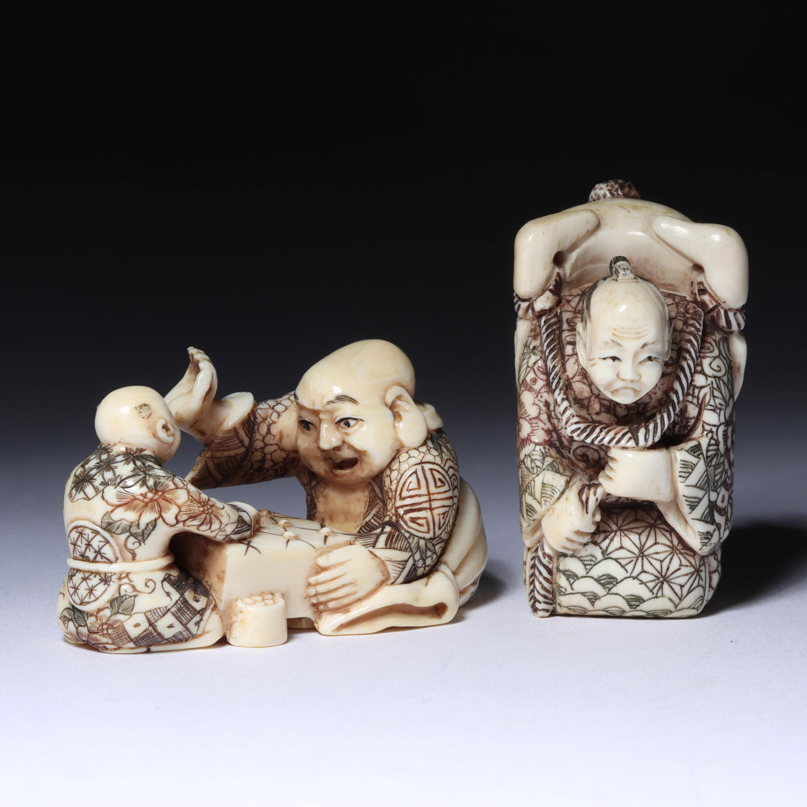 Japanese carved figural netsuke 2pc group: Buddha and child playing a board game with hand raised, (1 of 9)