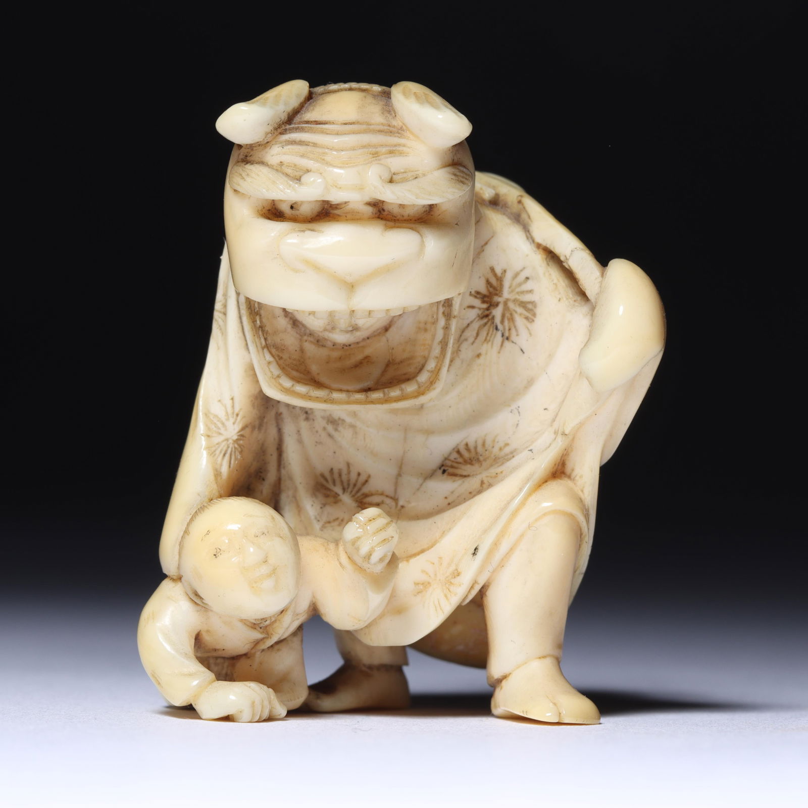 Japanese Meiji carved figure group netsuke: man with Shishi Foo dog mask, face showing within mouth, (1 of 7)