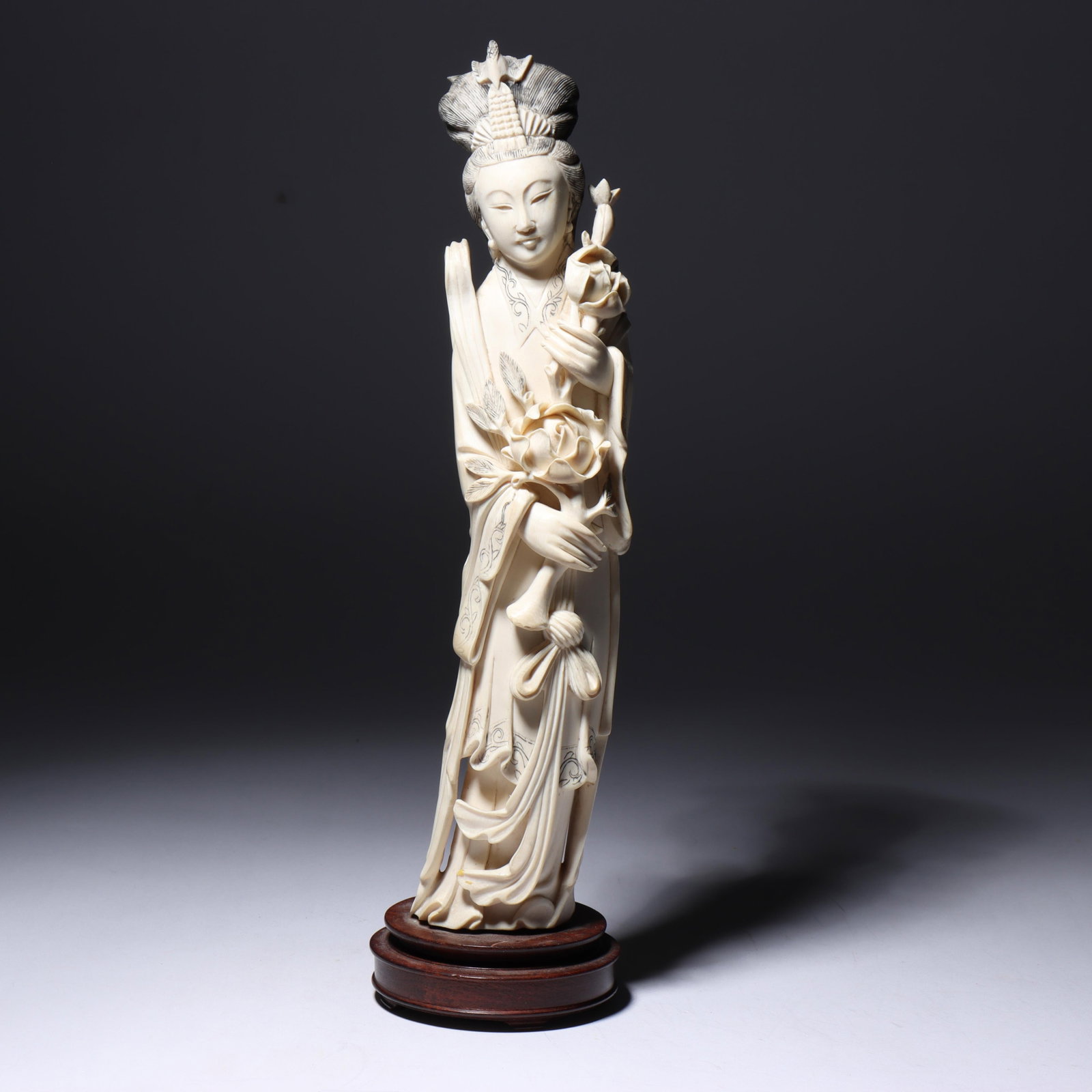 Chinese carved bone figure of Guanyin holding large flower, ribbon, engraved, border, black hair,: Chinese carved bone figure of Guanyin holding large flower, ribbon, engraved, border, black hair, wood base 12 1/2"H x 3 1/4"W
