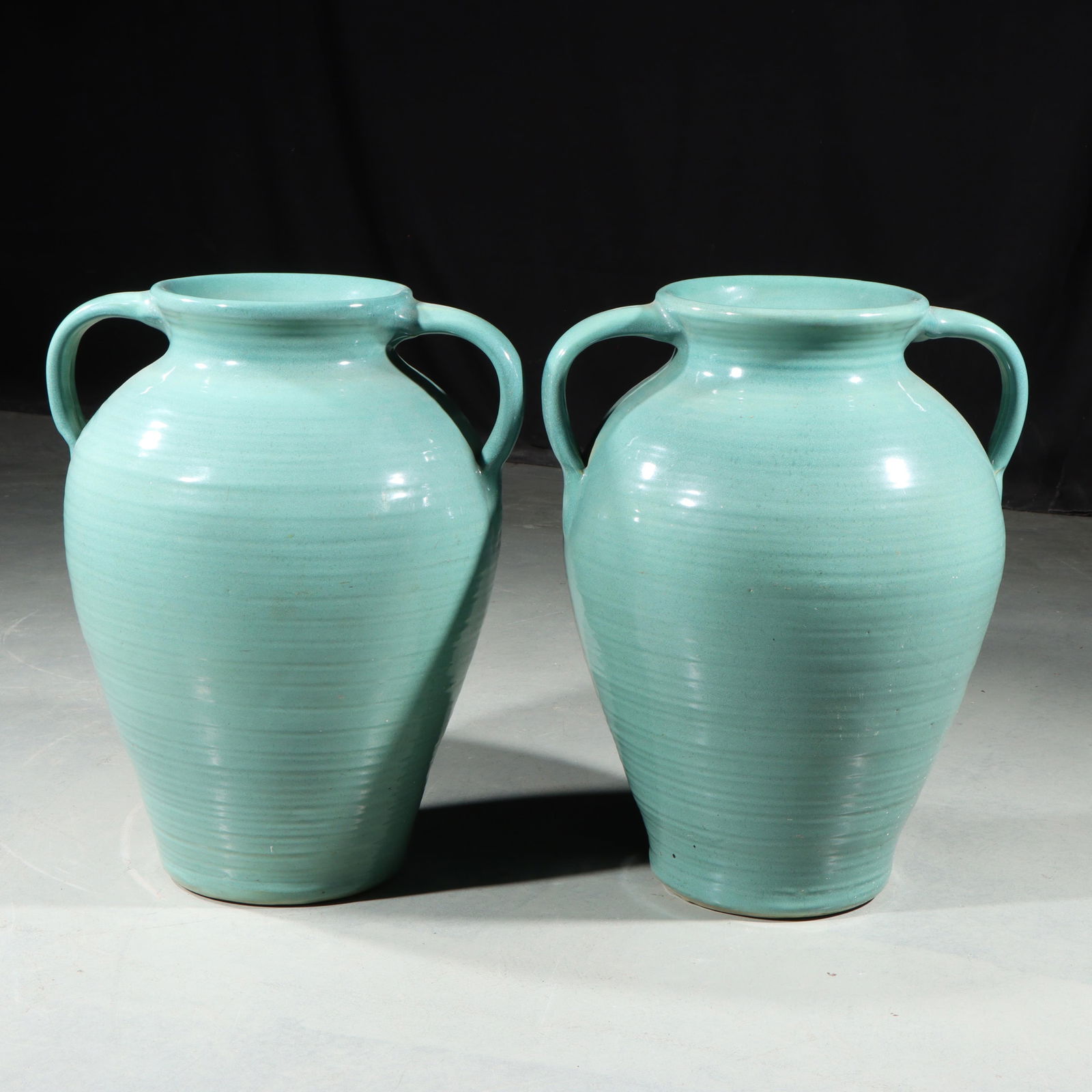 Pair of art pottery Bungalow Jars 18 1/2"H x 11"Diam. (one): Pair of art pottery Bungalow Jars Pair of green unmarked (possibly Zanesville) handled ribbed urns. Provenance: Charles Alexander, Indianapolis, IN 18 1/2"H x 11"Diam. (one)
