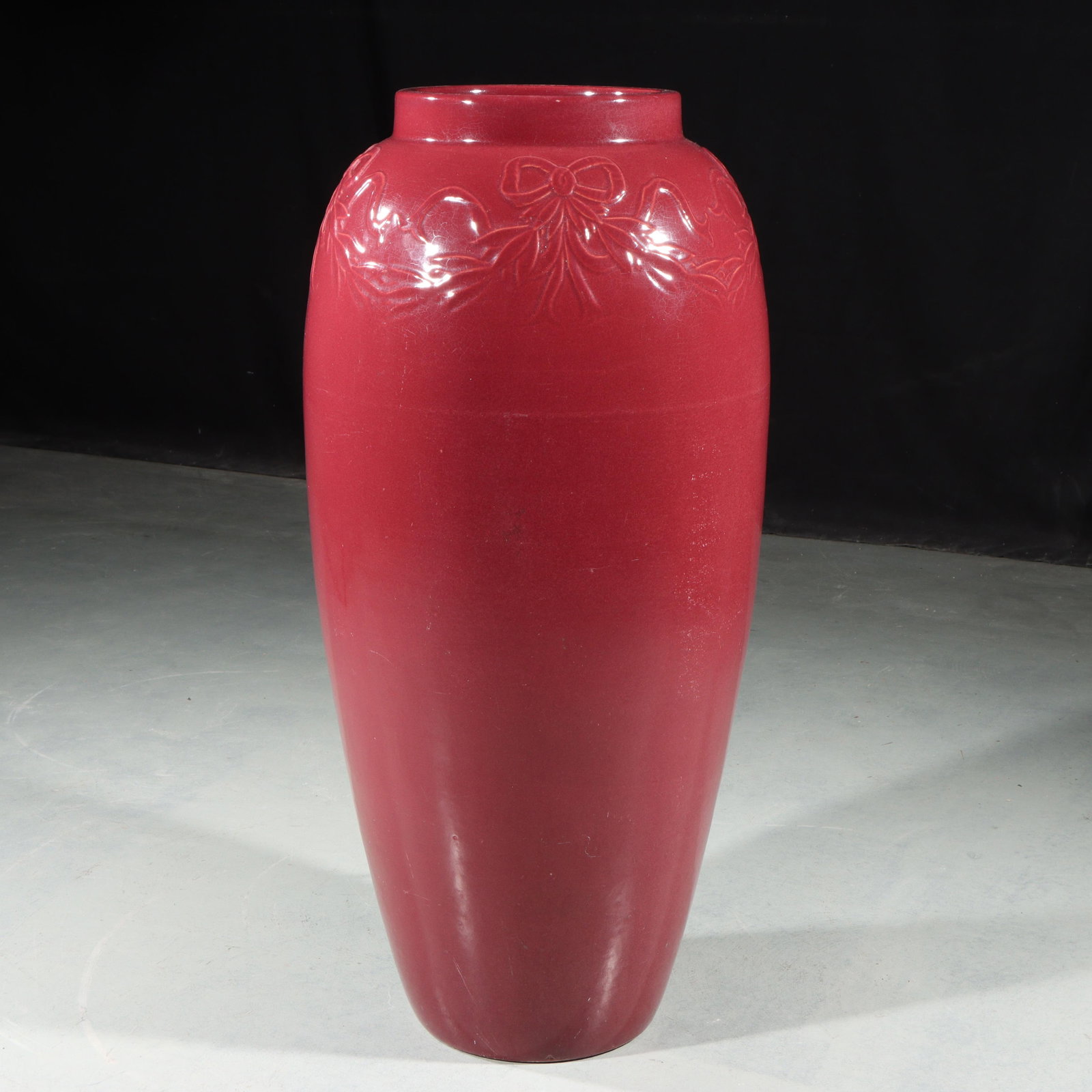 Bungalow Jar 26"H x 11"Diam.: Bungalow Jar Unmarked Robinson Ransbottom Pottery Co. Burgundy glazed Bungalow Jar with Ribbon & Bow decoration on rim. Unmarked. Provenance: Charles Alexander, Indianapolis, IN 26"H x 11"Diam.