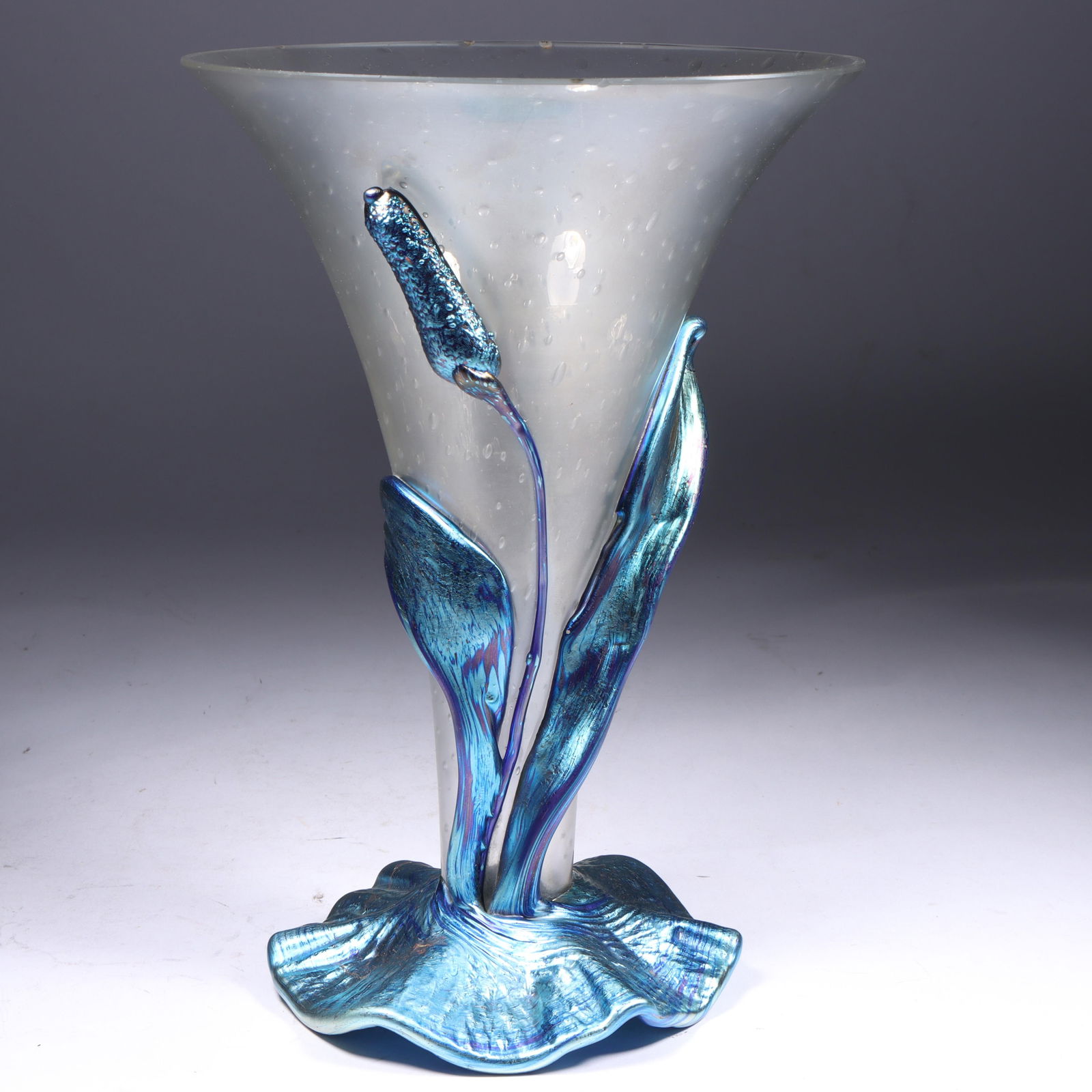 Loetz art glass vase with applied blue iridescent cattail motif on ruffle base over controlled: Loetz art glass vase with applied blue iridescent cattail motif on ruffle base over controlled bubble trumpet form. Signed with square Czechoslovakia acid stamp under base. Two small nicks to rim. 9 1