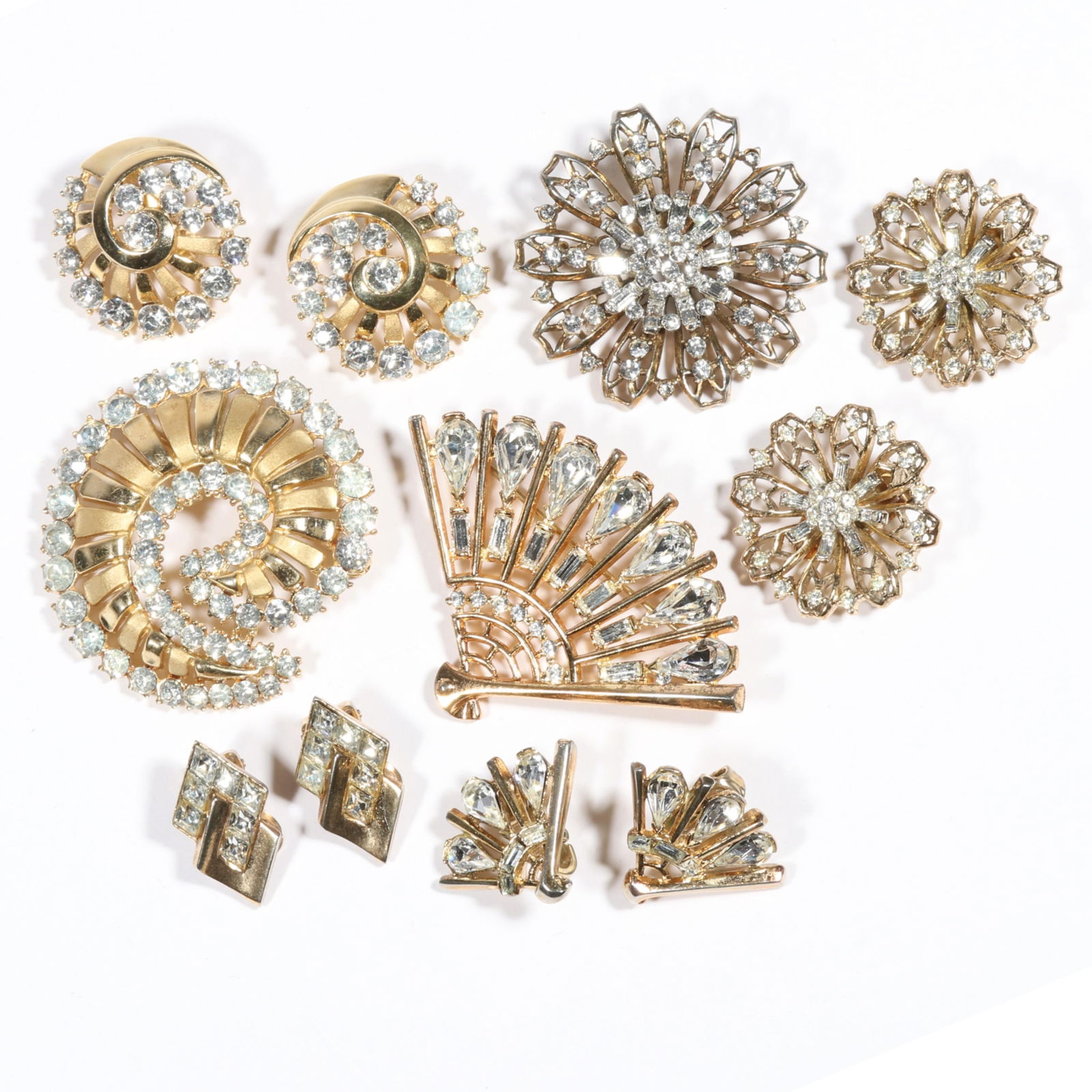 7pc Crown Trifari Retro rhinestone crystal costume jewelry group with matching sets of brooches and: 7pc Crown Trifari Retro rhinestone crystal costume jewelry group with matching sets of brooches and earrings plus one bonus pair of earrings. Light wear to gold tone. 1 5/8"H x 2 3/8"W (fan brooch)