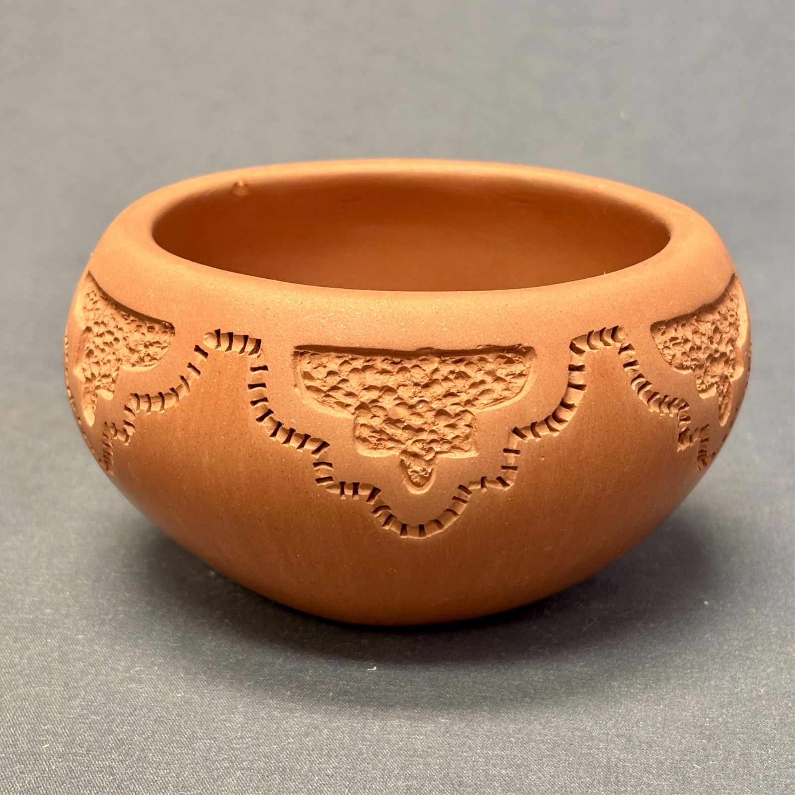 Caroline Carpio, Authentic Isleta Pueblo Carved Pot 3" high x 4 1/2" wide x 3 1/2" diameter at mouth: Caroline Carpio, Authentic Isleta Pueblo Carved Pot Elegant handmade red pot by Isleta Pueblo artist Caroline Carpio. The beautifully carved design on the upper area of the pot is unfinished clay whil