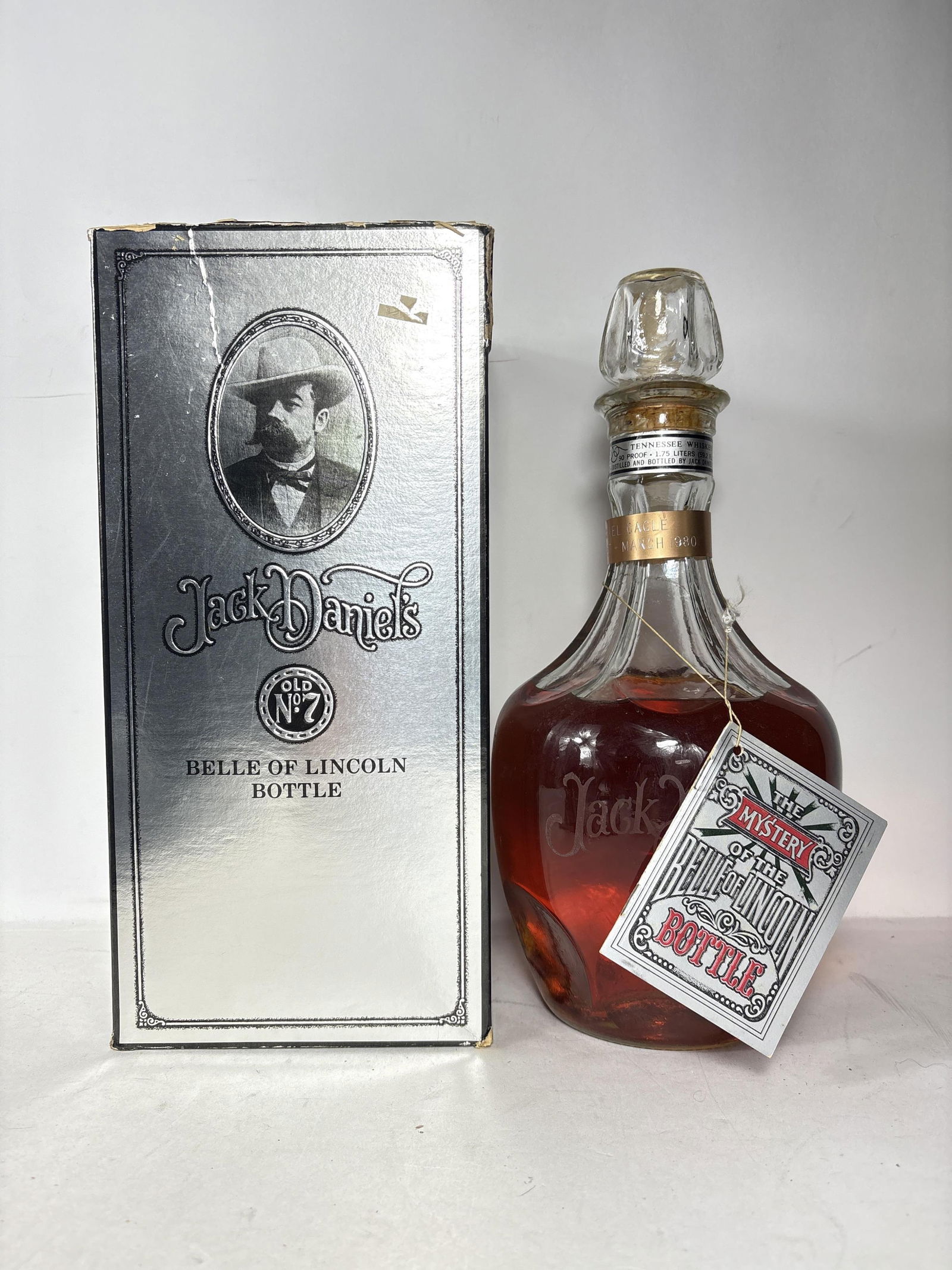 1980 Jack Daniels Old No7 The Mystery of the Belle of Lincoln Bottle: 1980 Jack Daniels Old No7 The Mystery of the Belle of Lincoln Bottle ID Tag engraved Bottling number 7 March 1980 Seal broken on bottle but doesn?t appear to have been opened Box is damaged. ALL ALCOH