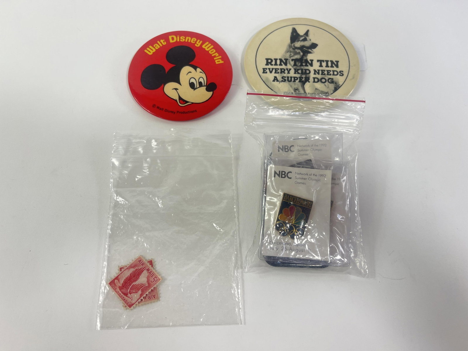Lot of 6 pins and a Chris Jagger pendant. Disney, NBC, Unforgiven, Rin Tin Tin, and two stamps,: Lot of 6 pins and a Chris Jagger pendant. Disney, NBC, Unforgiven, Rin Tin Tin, and two stamps Provenance: Connie DeNave Estate