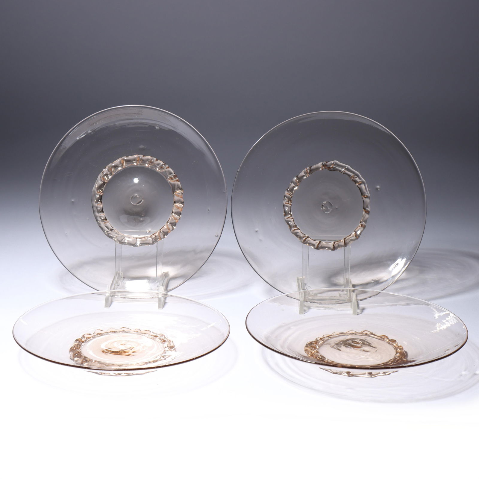 Four Maestri Vetrai Muranesi (MVM) Murano Cappellin ca. 1925 salad/dessert plates with tooled ribbon: Four Maestri Vetrai Muranesi (MVM) Murano Cappellin ca. 1925 salad/dessert plates with tooled ribbon foot in pale smoke Provenance: Fort Wayne Museum of Art, Fort Wayne, Indiana. 1 1/4"H x 6 1/2"Diam.