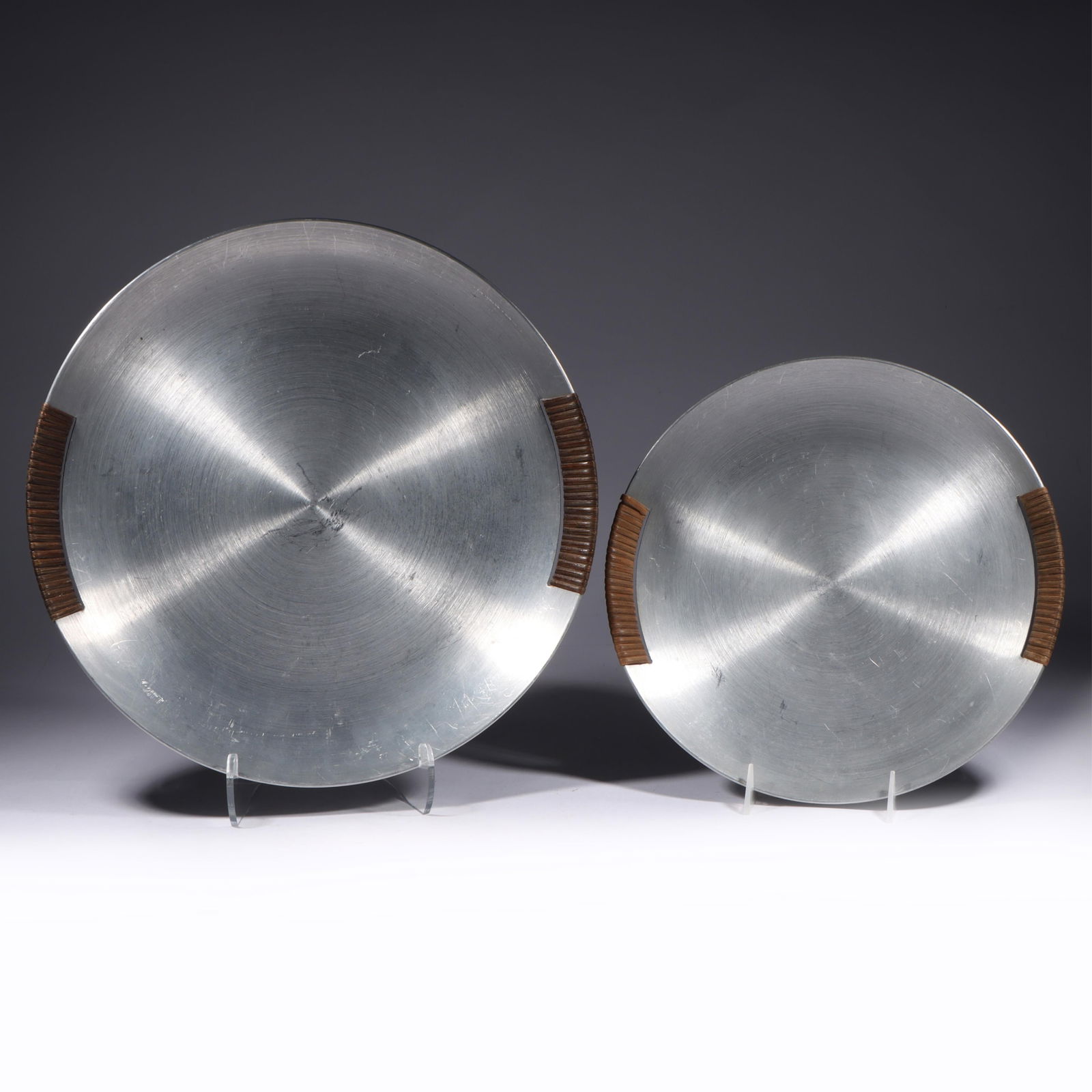 Two Russel Wright Spun Aluminum w/Raffia Handled Trays 14 1/2"Diam. (largest): Two Russel Wright Spun Aluminum w/Raffia Handled Trays Circa 1935; Both stamped "RUSSEL WRIGHT" Provenance: Charles Alexander, Indianapolis, IN 14 1/2"Diam. (largest)