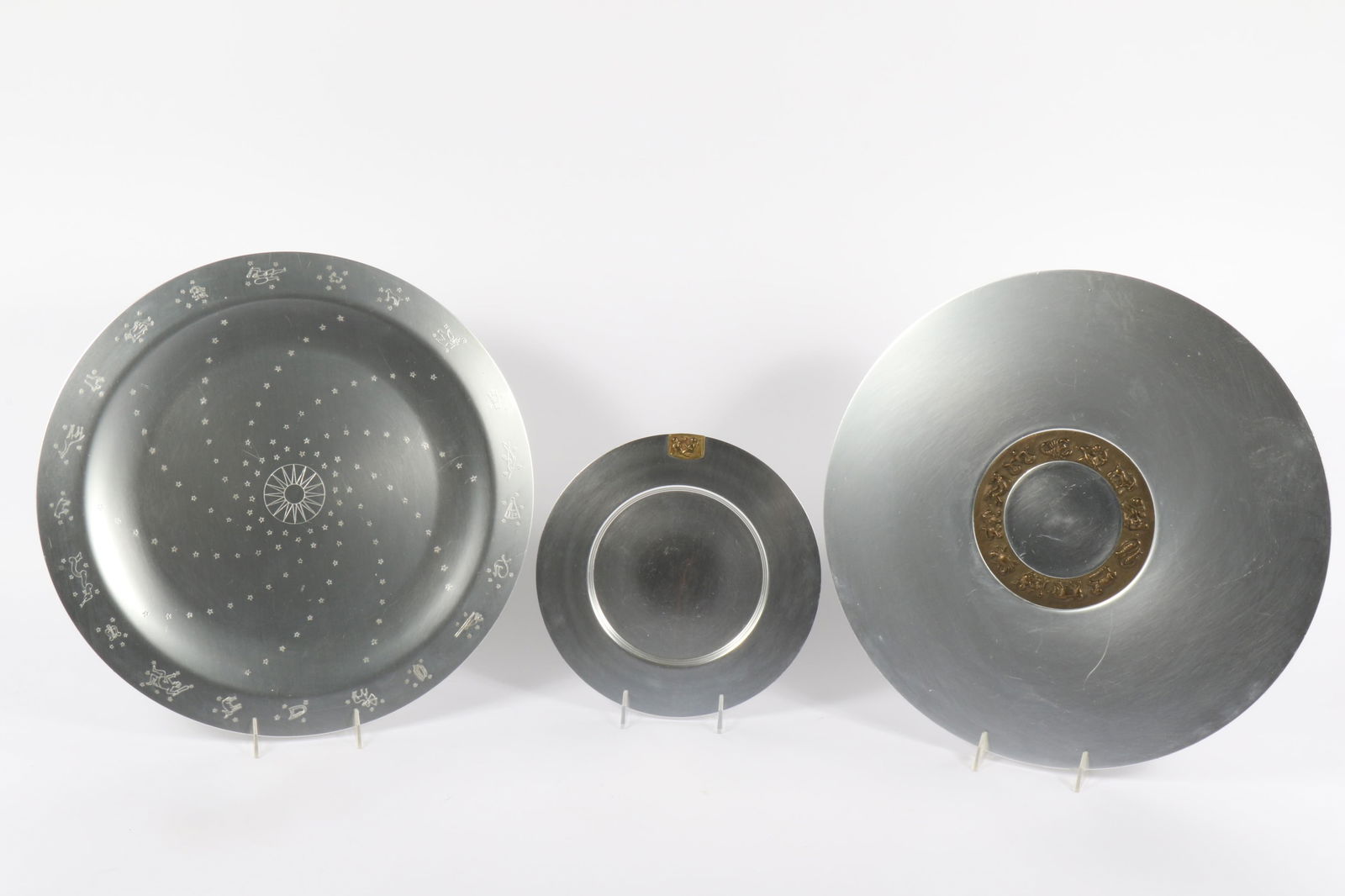 Kensington Lurelle Guild 2 Aluminum/Brass Trays and Plate 18" Diam. (Largest): Kensington Lurelle Guild 2 Aluminum/Brass Trays and Plate #7107 18" Dia. "Constellation" Platter; #7100 18" Dia. "Zodiac" Platter; #7315-D 10" Dia. "Gemini" Sandwich Plate. Provenance: Charles Alexand